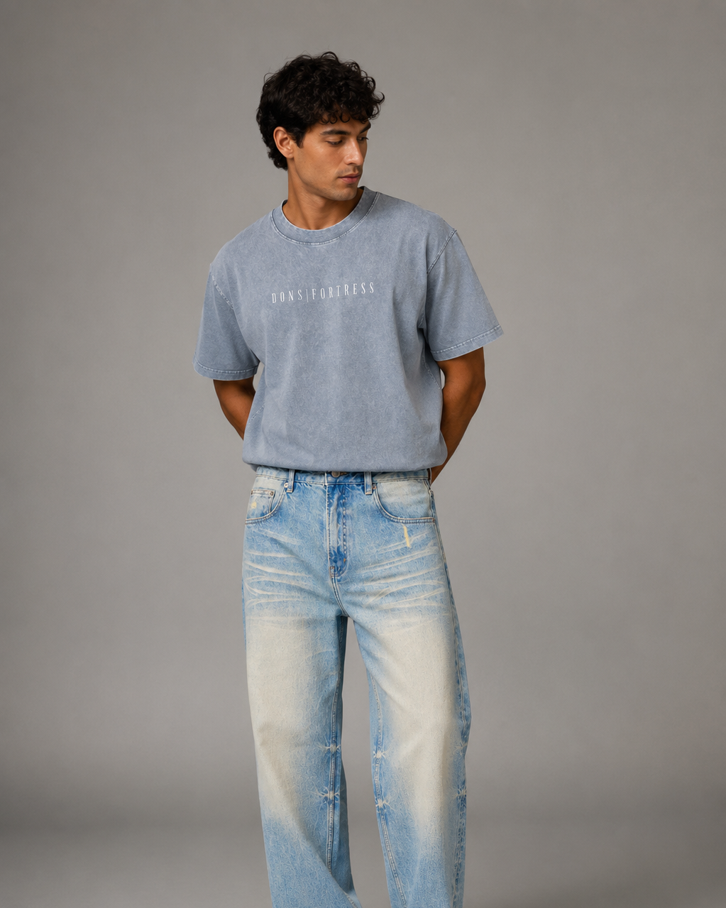 Man wearing a light blue t-shirt and jeans on a gray background