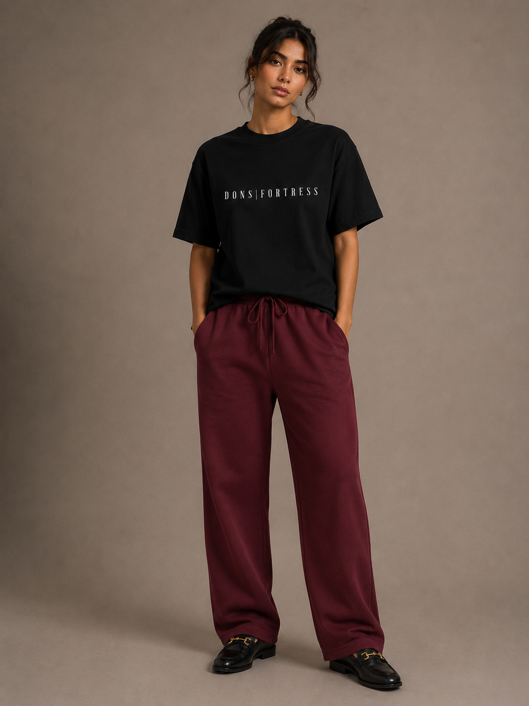 Person wearing a black t-shirt and maroon pants against a plain background