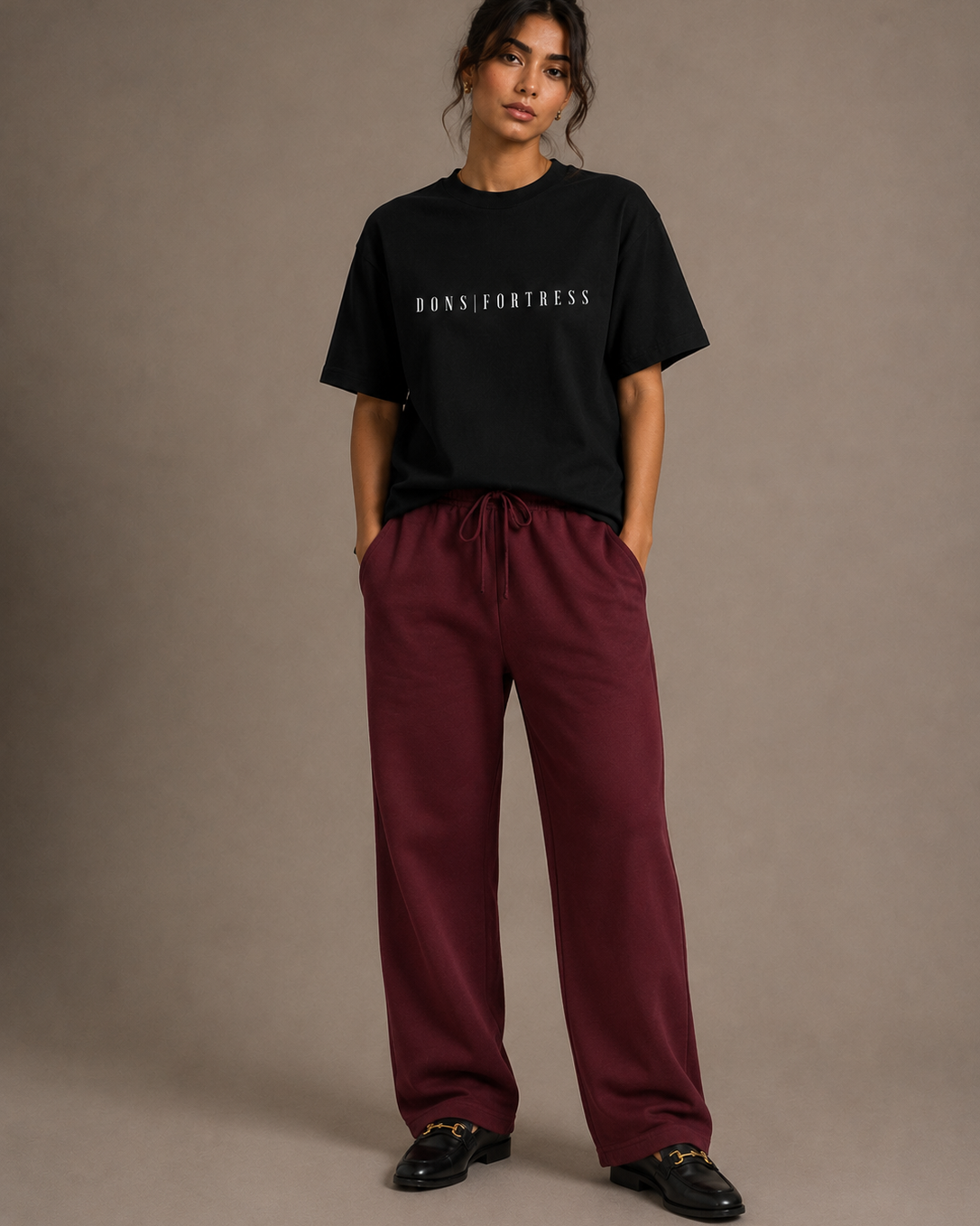 Person wearing a black t-shirt and maroon pants against a plain background