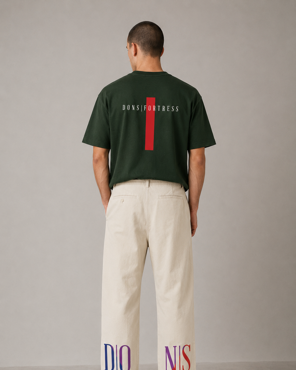 Person wearing a green t-shirt with text and white pants with printed text on a plain background