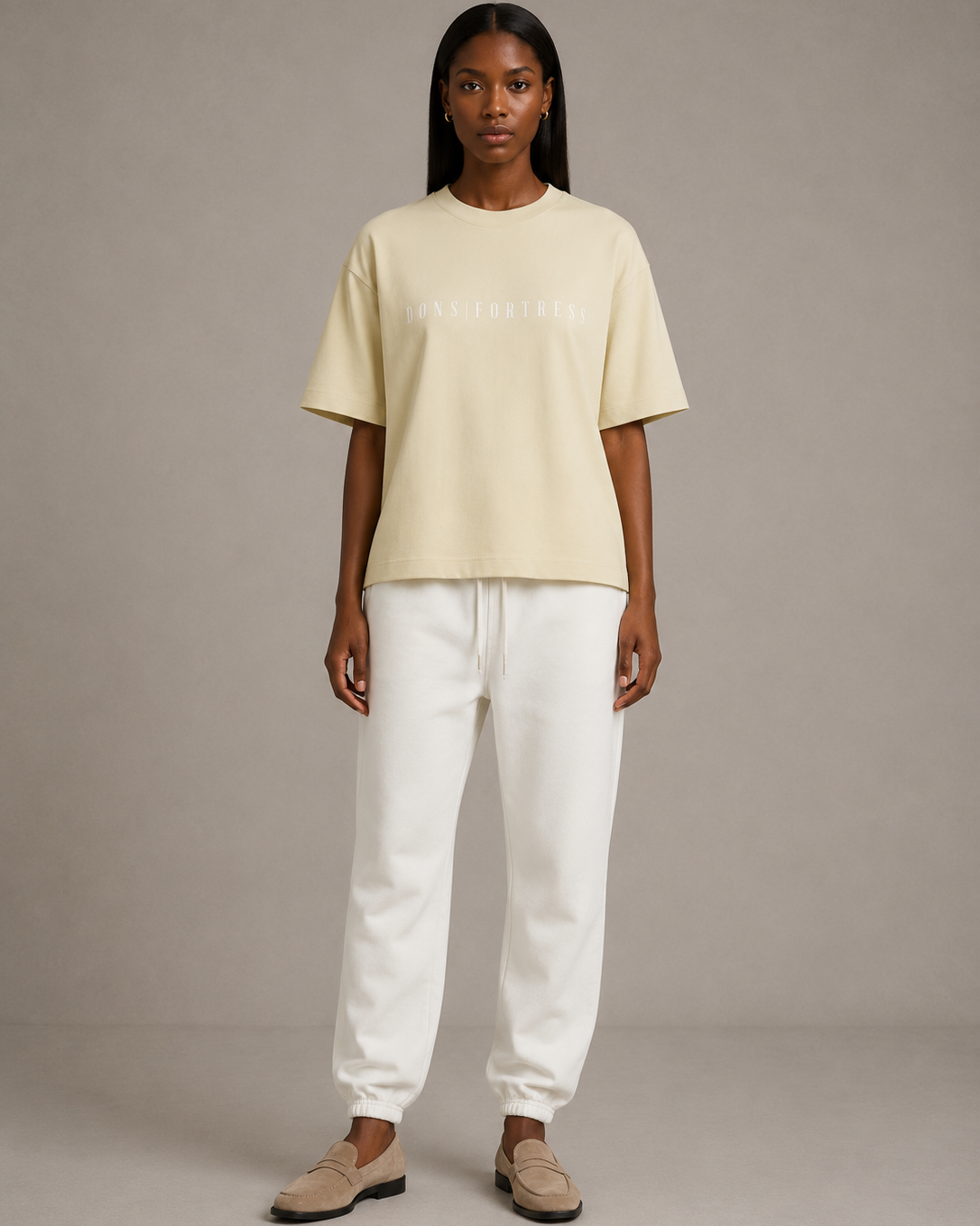 Person wearing a light yellow t-shirt and white pants on a plain background