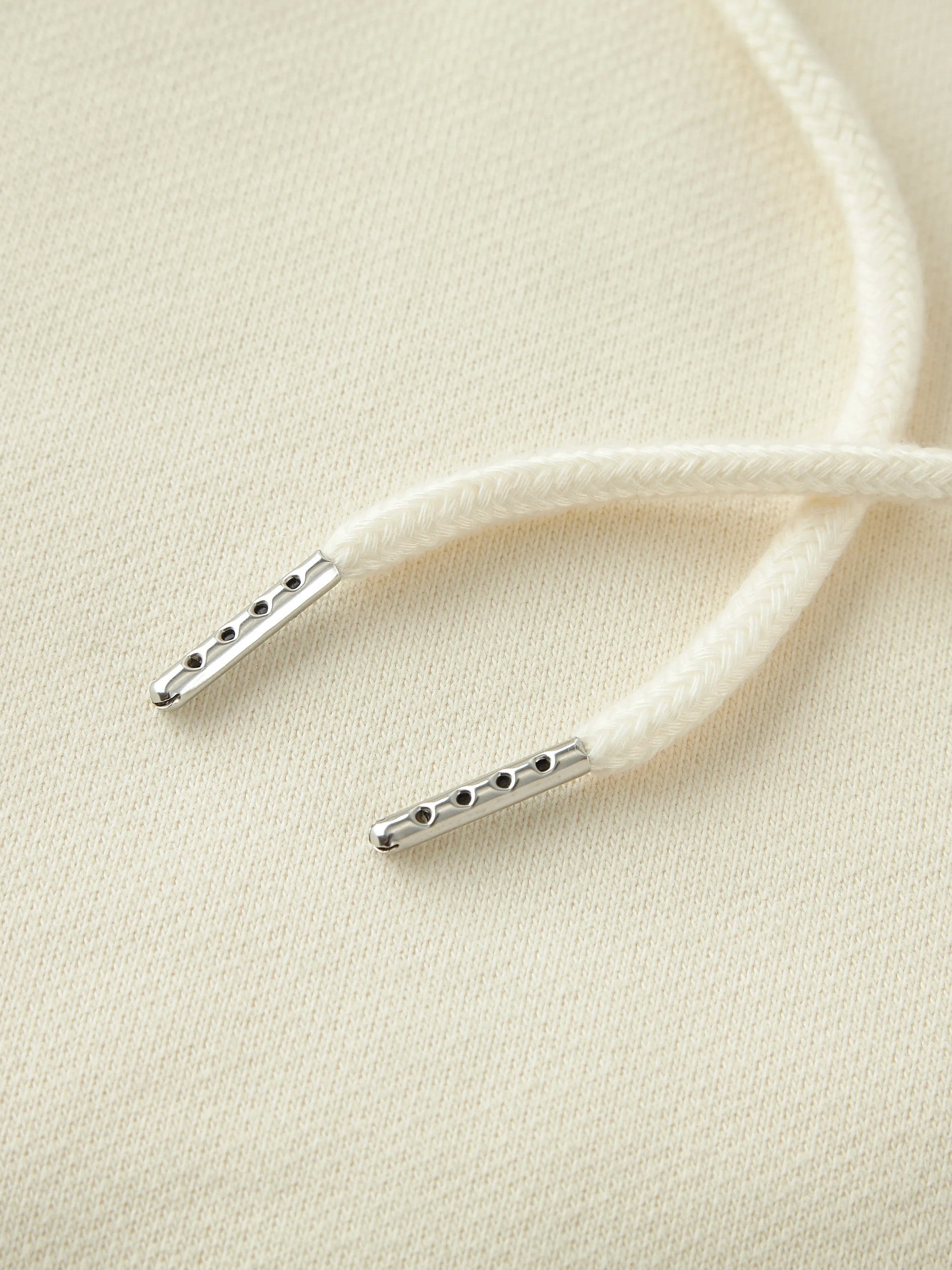 Close-up of white shoelaces with metal lace locks on a beige background