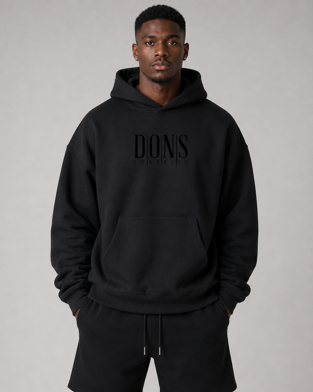 Man wearing a black hoodie with logo on a gray background