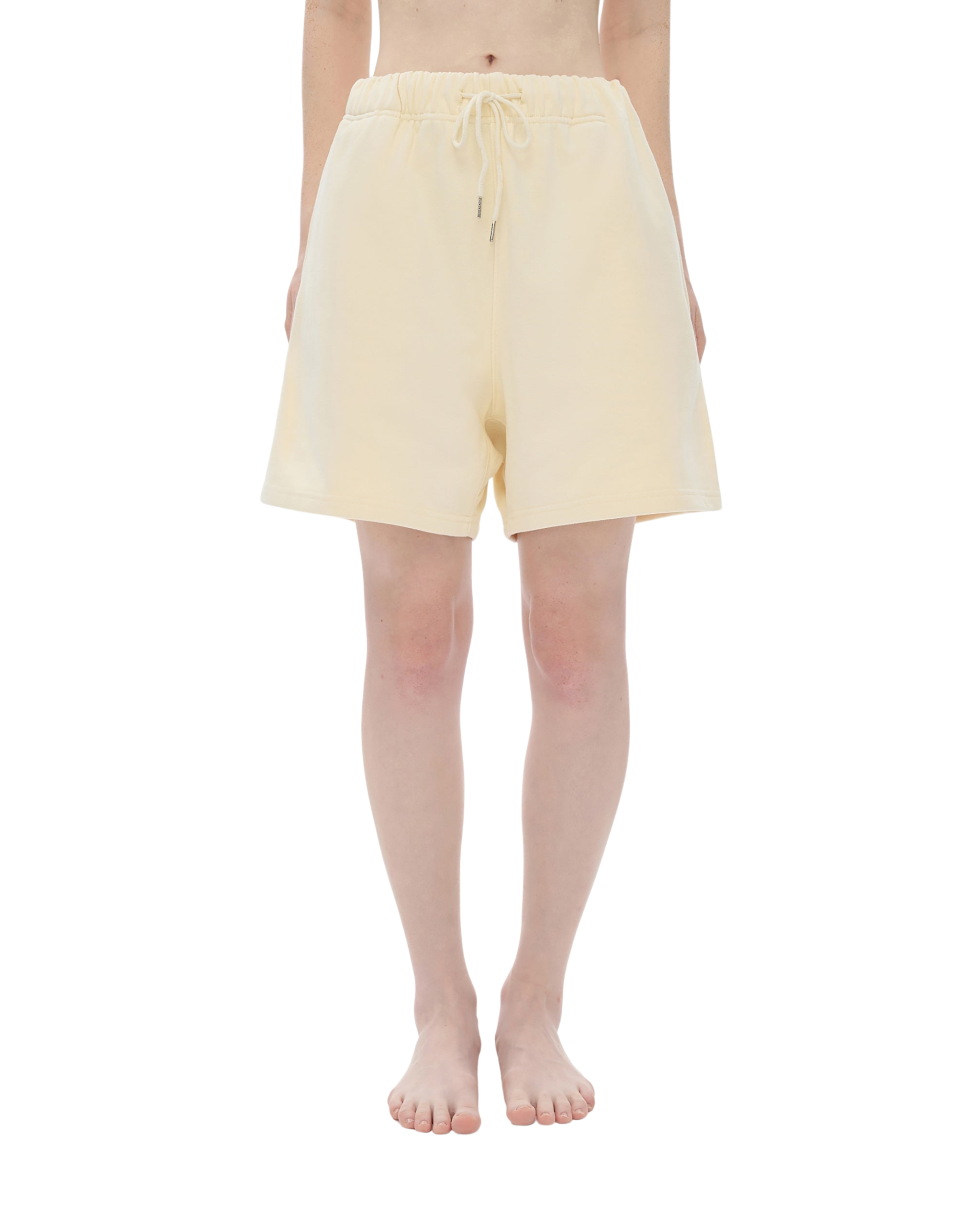 Person wearing light yellow shorts on a white background
