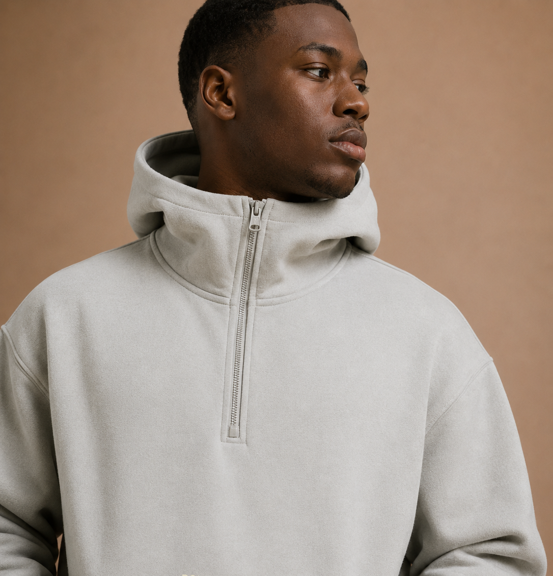 Man wearing a light gray hoodie with a brand logo on a beige background