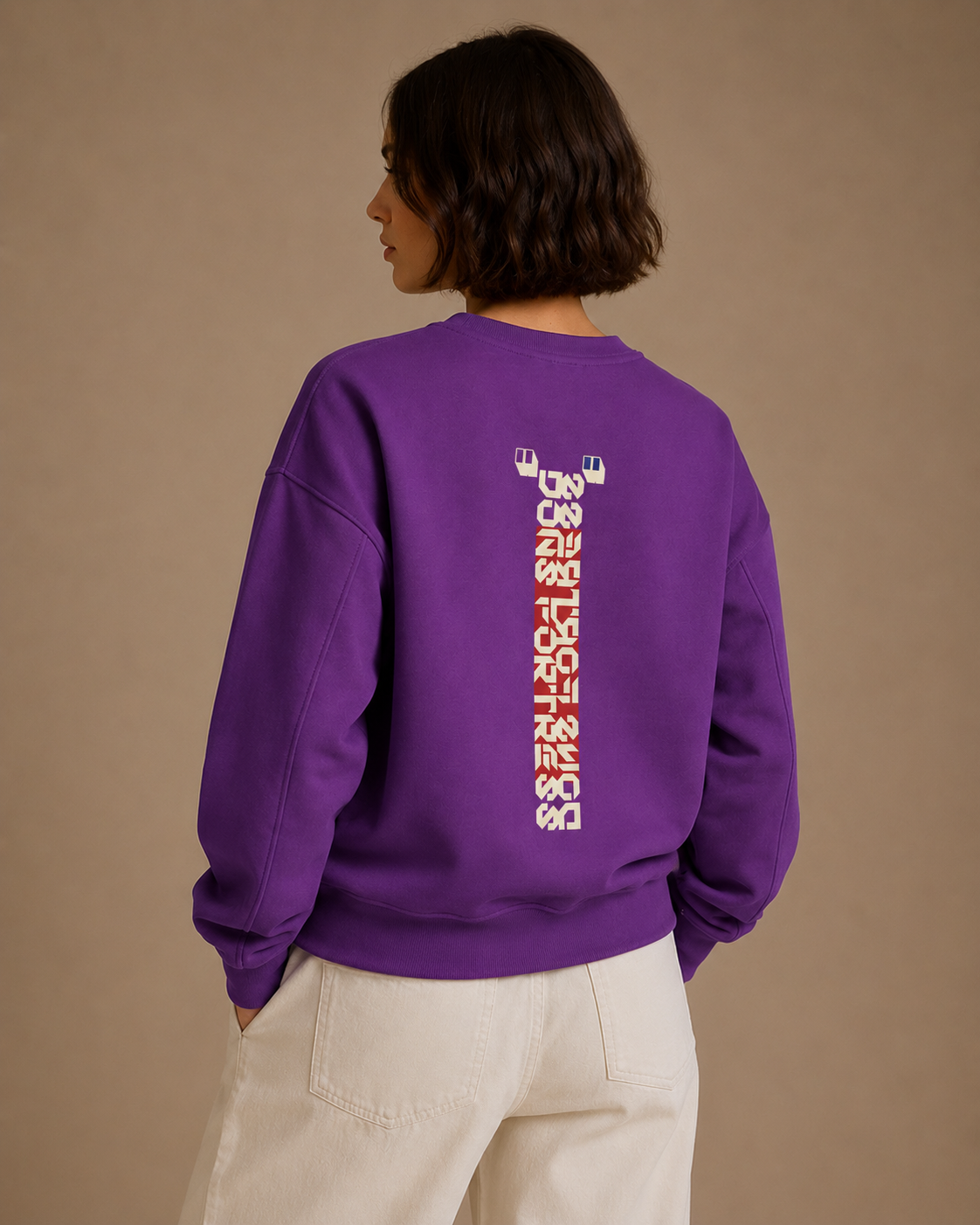 Person wearing a purple sweatshirt with text on the back against a beige background