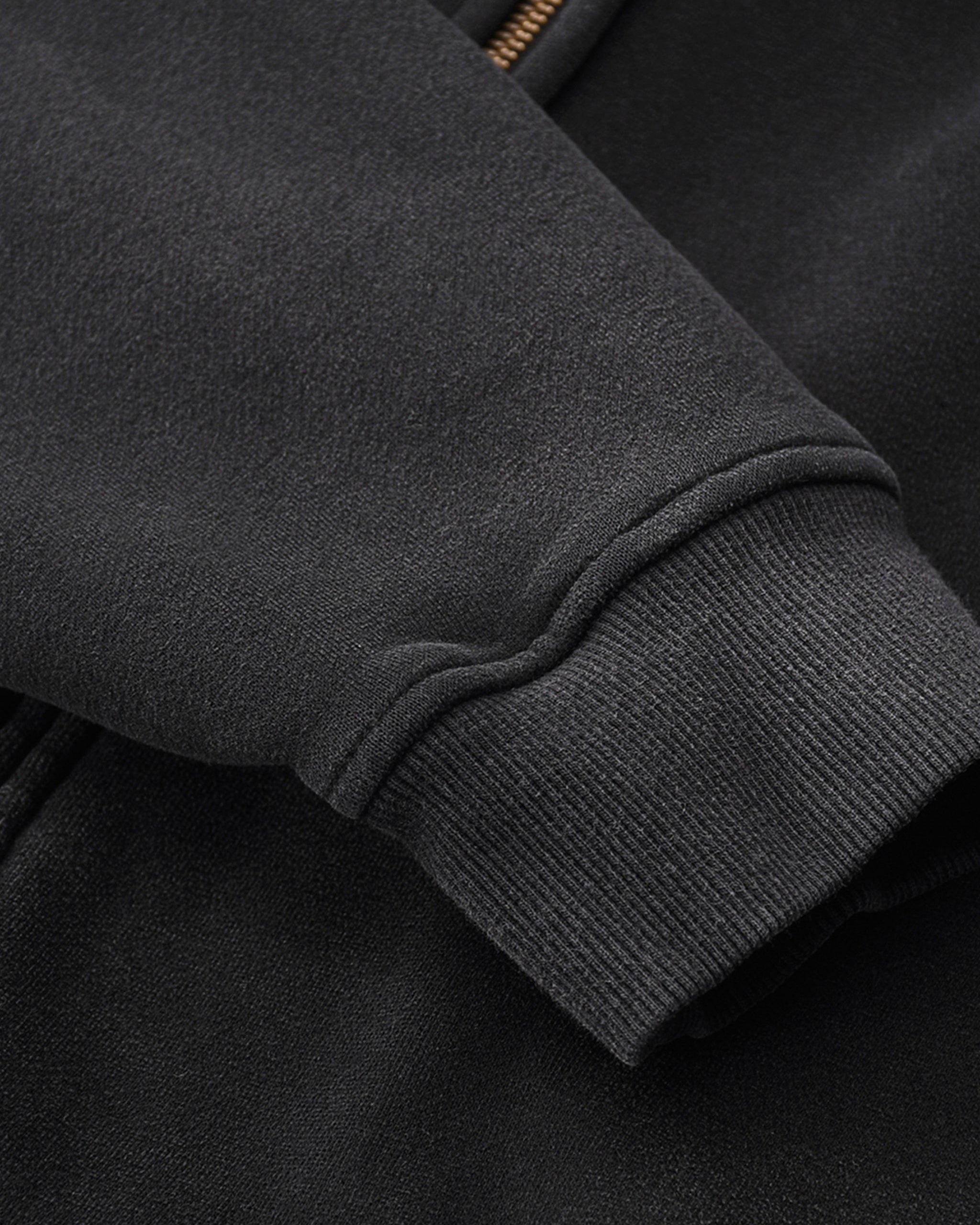 Close-up of a dark gray jacket sleeve with a zip detail.