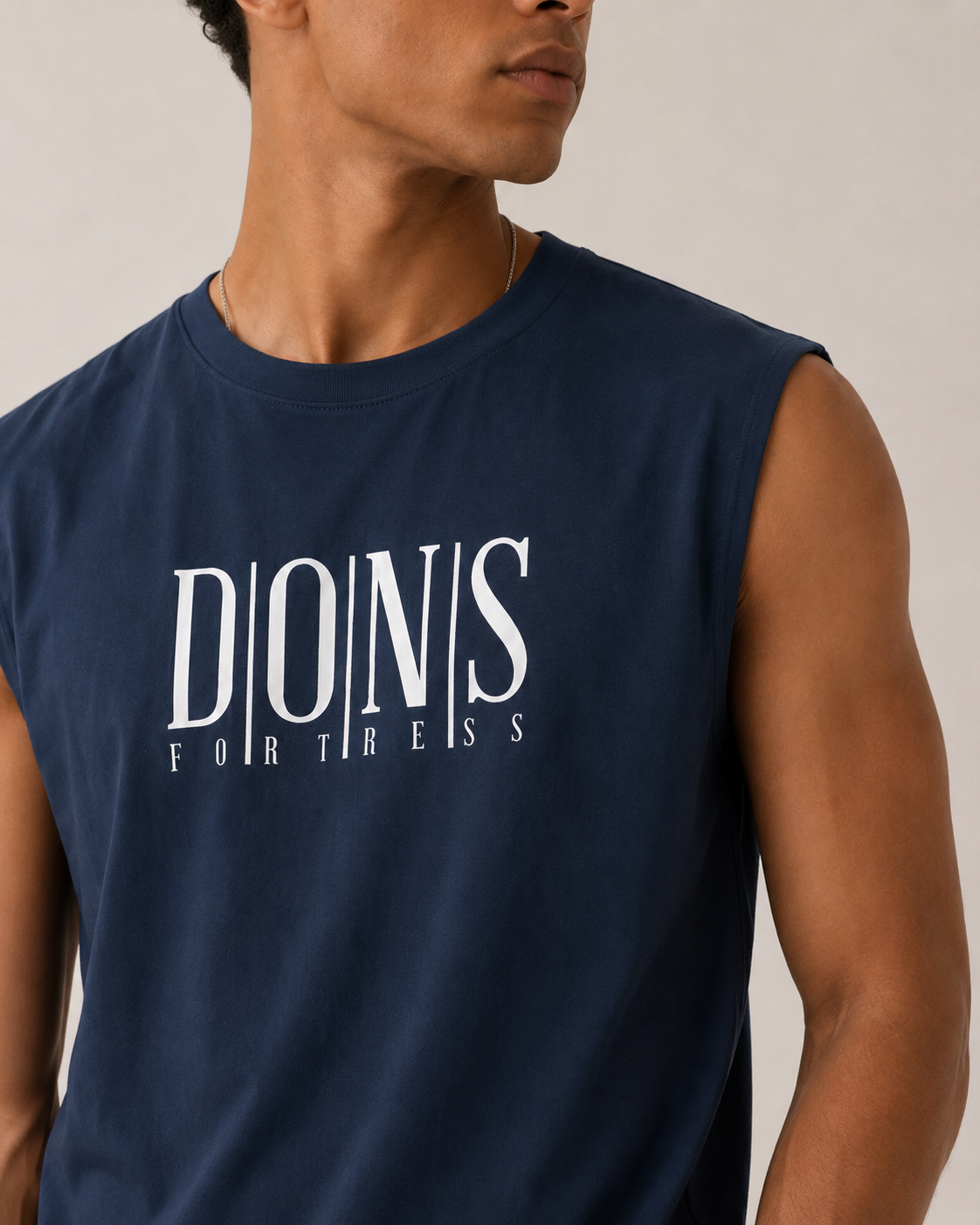 Man wearing a navy sleeveless shirt with 'DONS FORTRESS' text on a neutral background