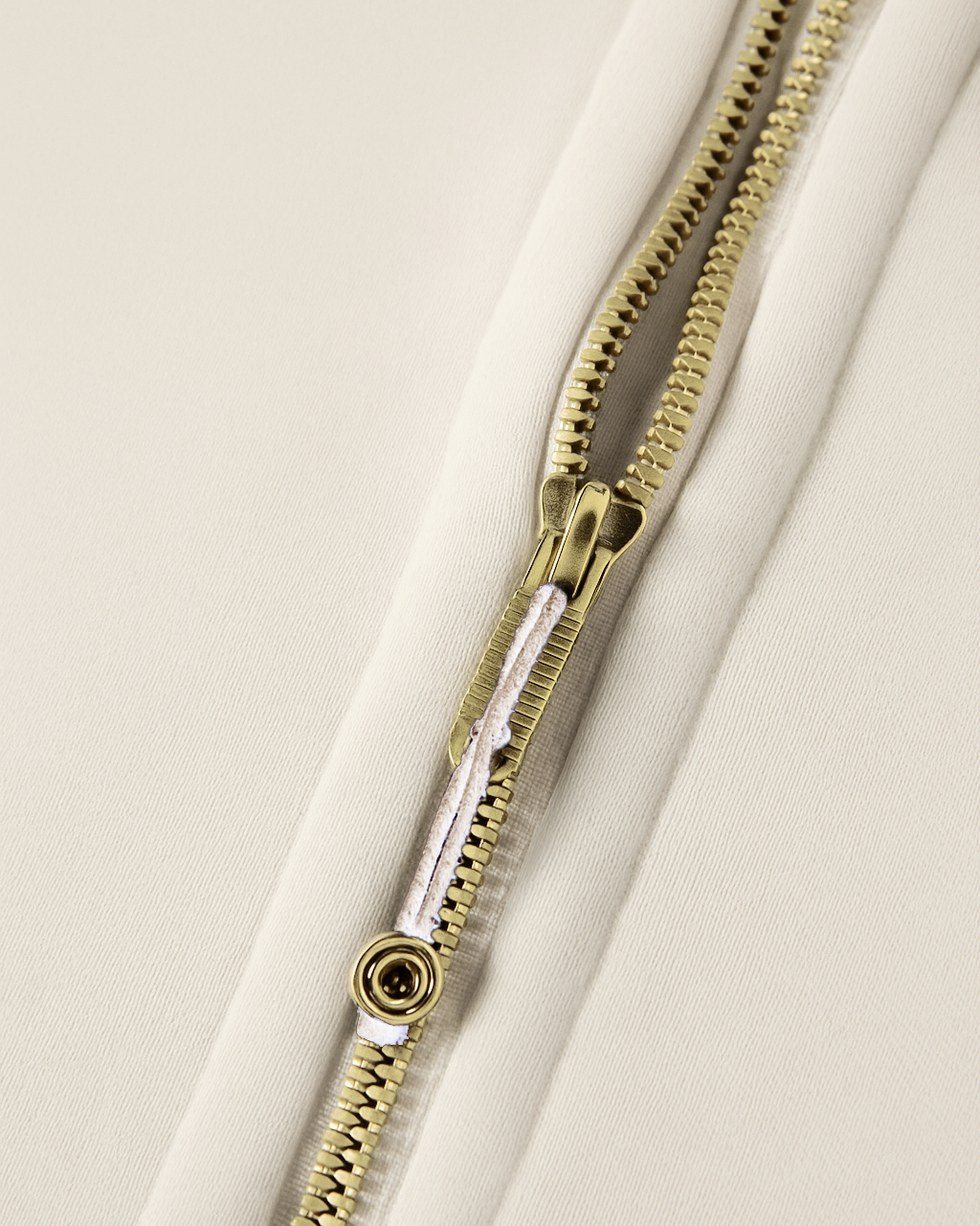 Close-up of a gold zipper on a beige background