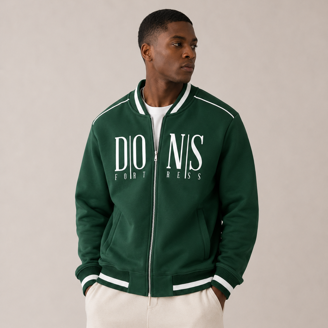 Man wearing a green jacket with 'Dons Fortress' branding on a beige background