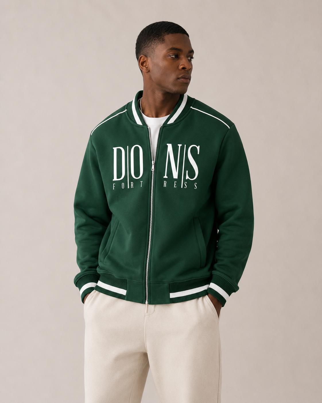 Man wearing a green jacket with 'Dons Fortress' branding on a beige background