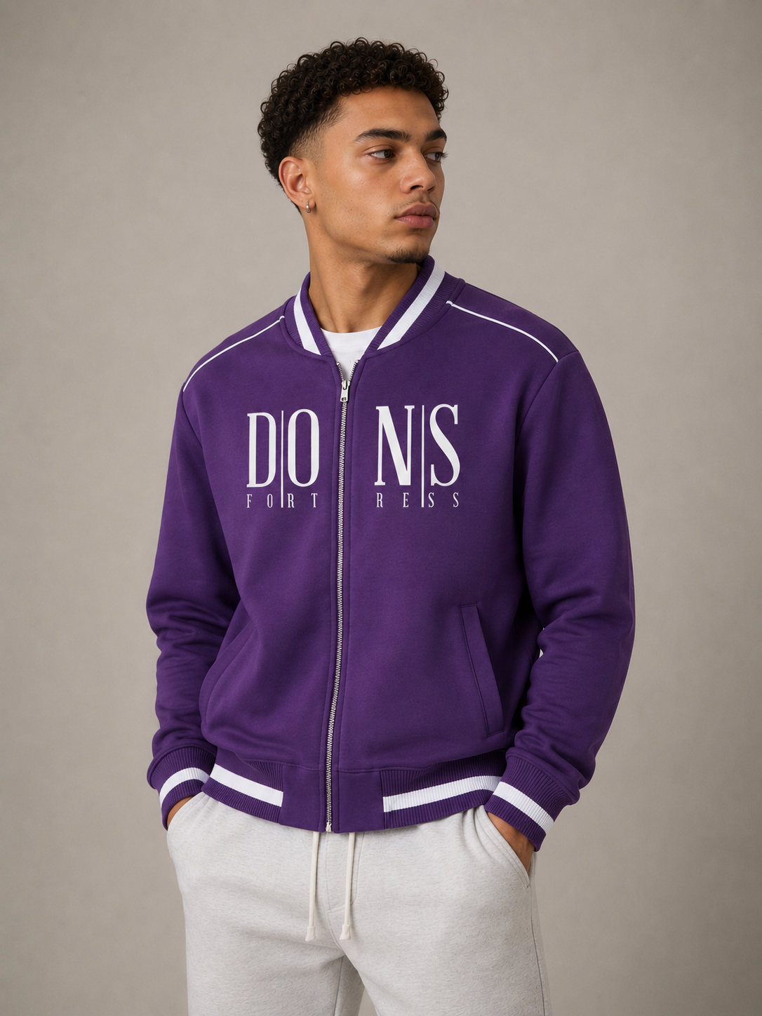 Person wearing a purple varsity jacket with white text on a neutral background