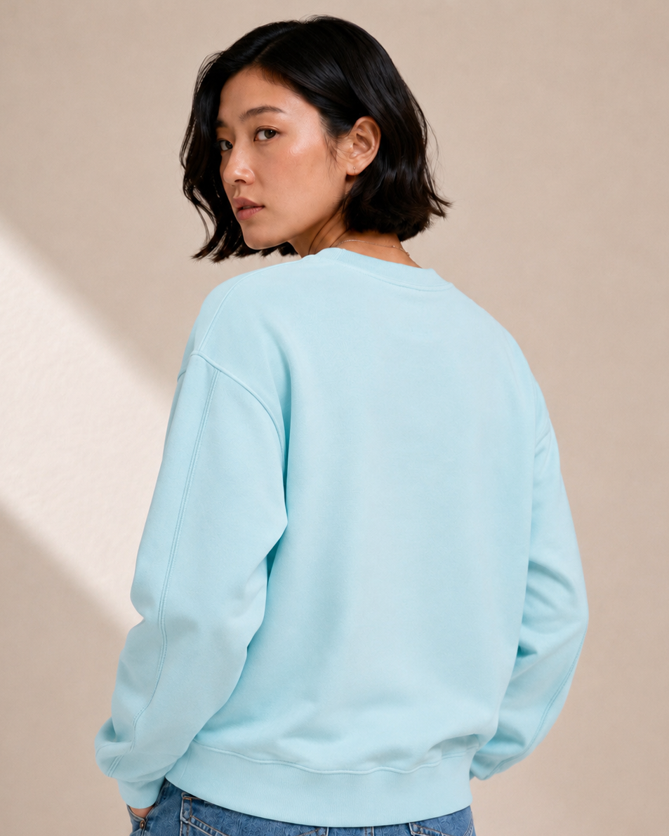 Person wearing a light blue sweatshirt and jeans on a beige background