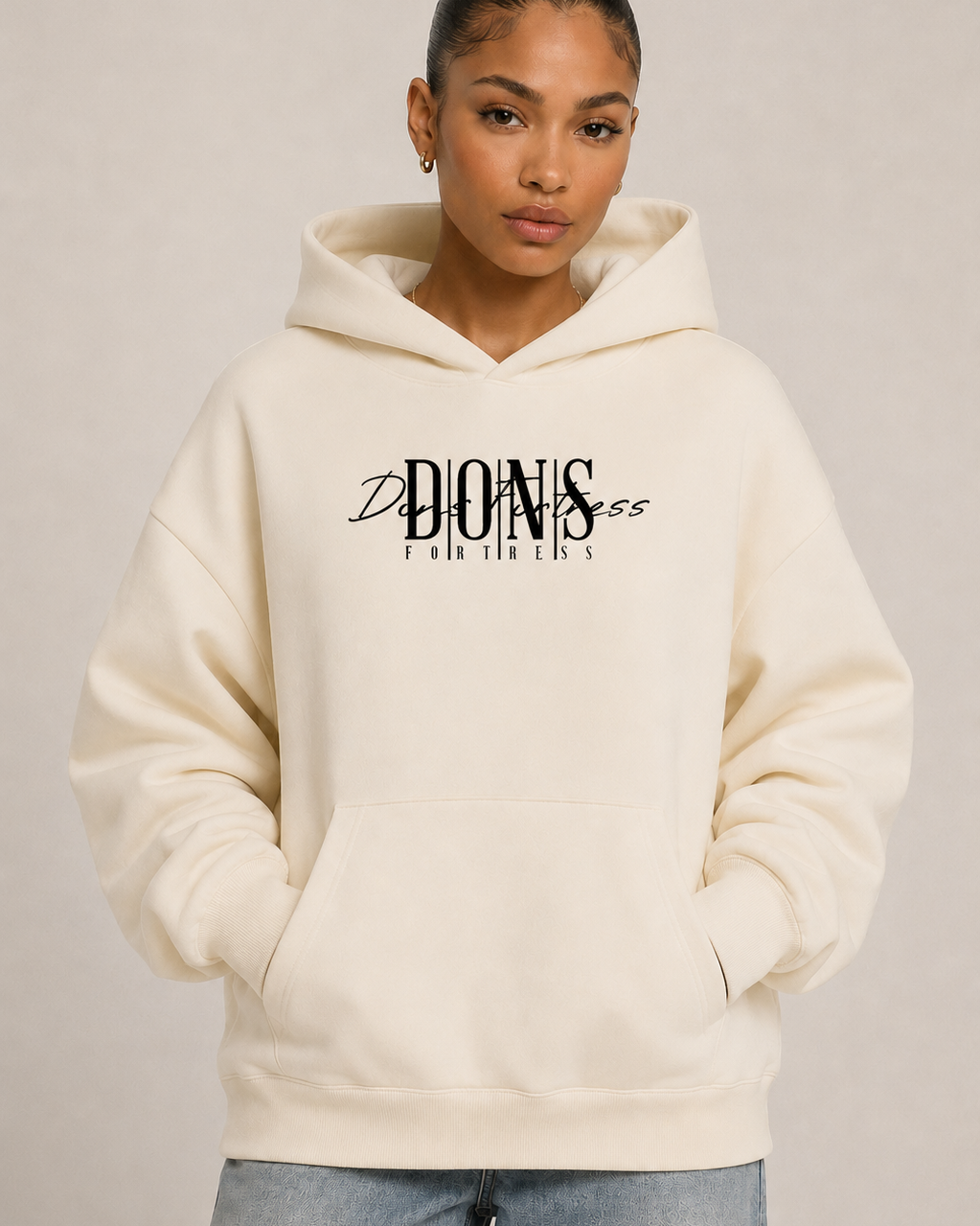 Person wearing a beige hoodie with text on it against a plain background