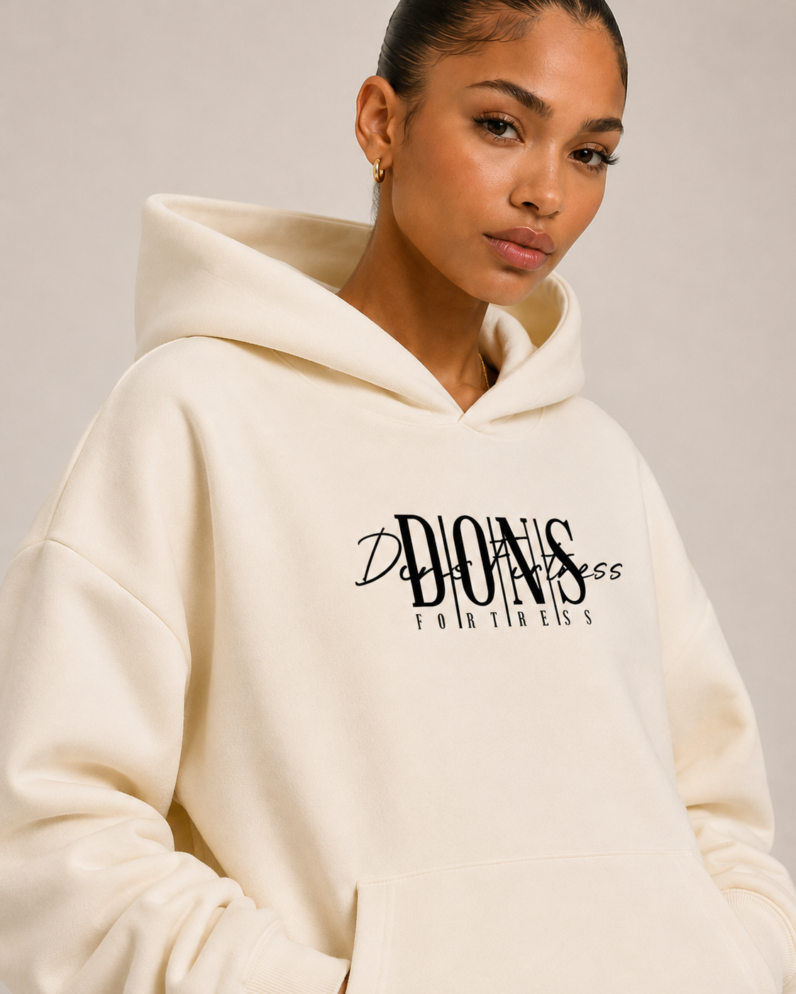 Woman wearing a cream hoodie with text on it against a plain background
