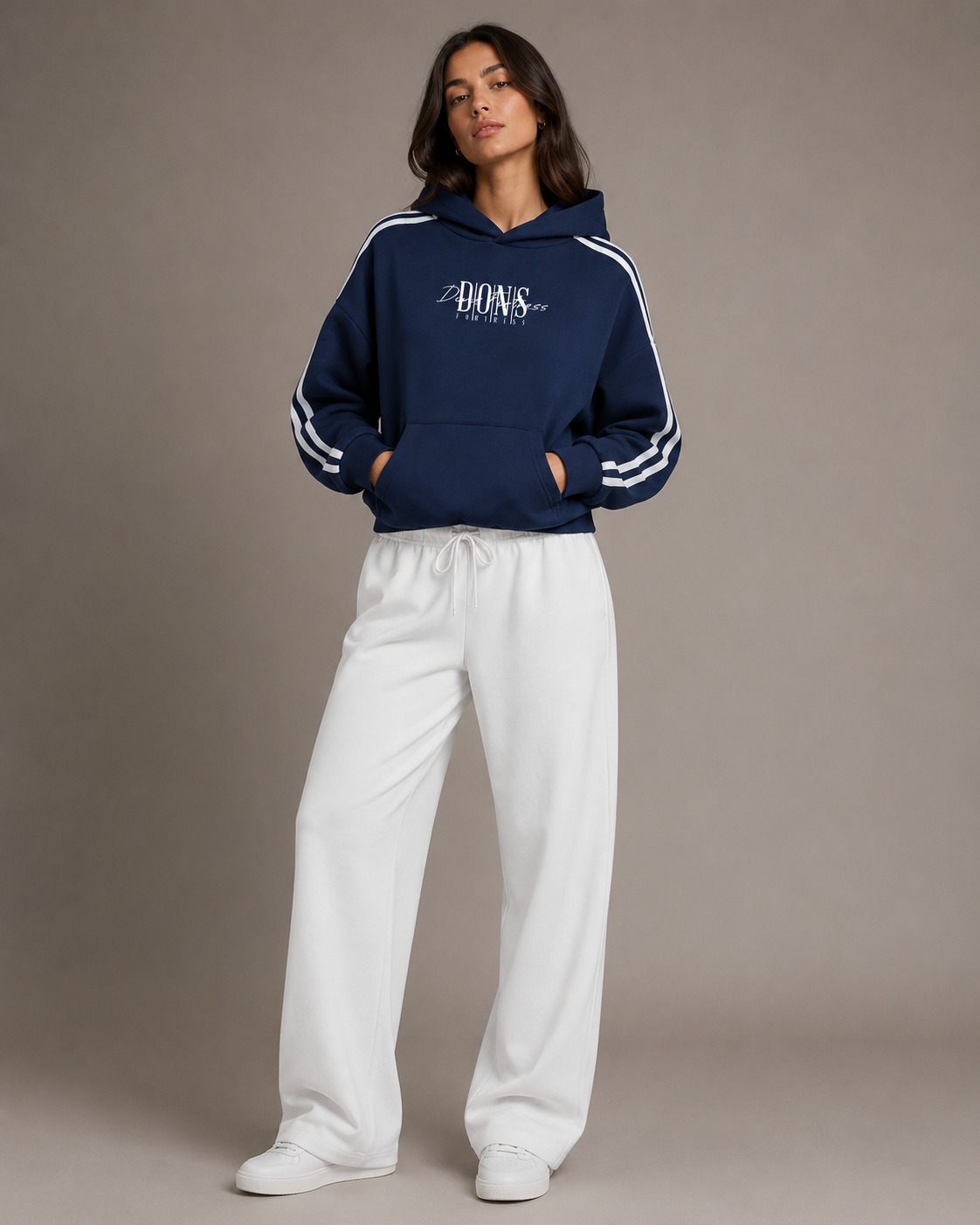 Person wearing a navy hoodie with white stripes and white pants on a brown background