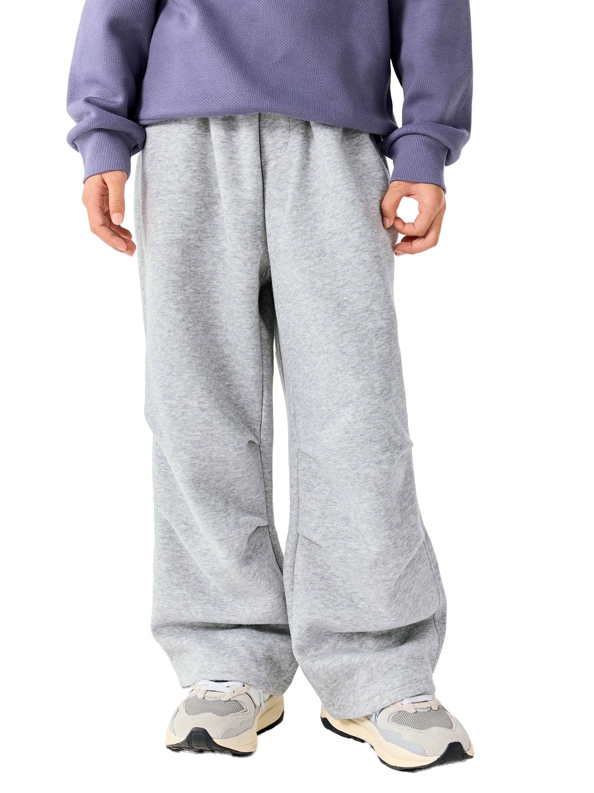 Person wearing a purple sweatshirt and gray sweatpants on a white background