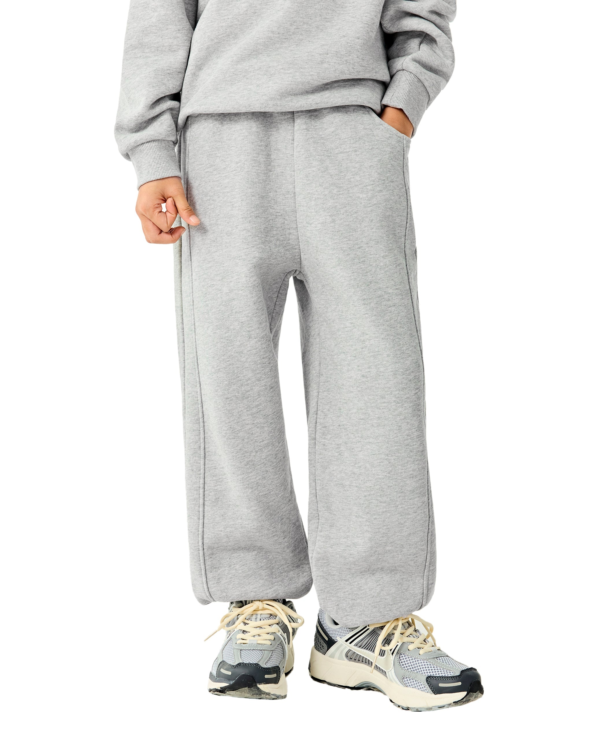 Person wearing a gray tracksuit with white sneakers on a white background