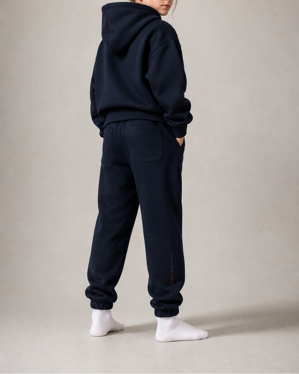 Person wearing a navy blue hoodie and pants on a plain background