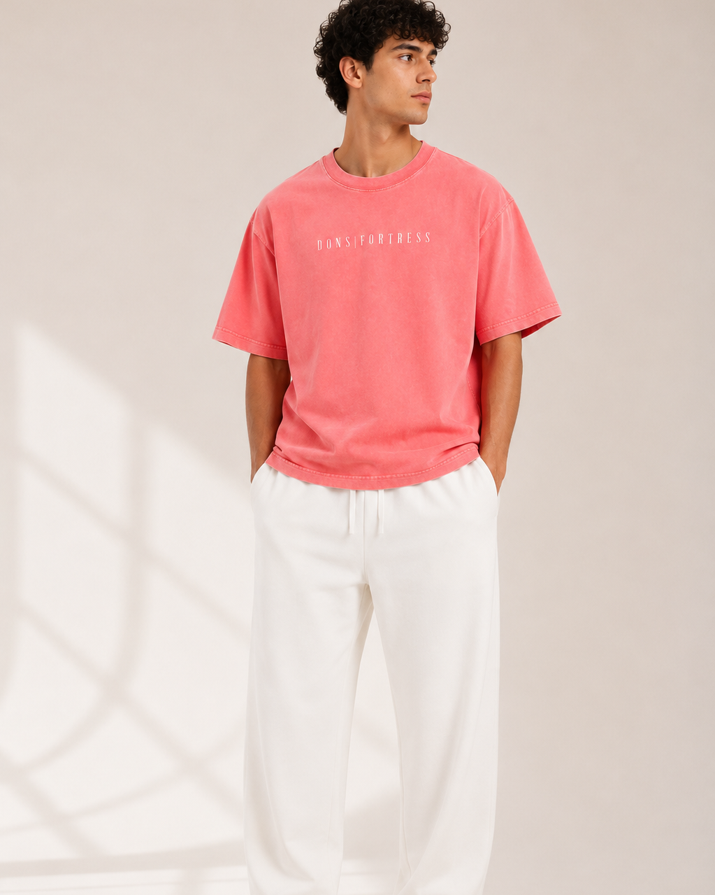 Person wearing a pink t-shirt and white pants on a neutral background