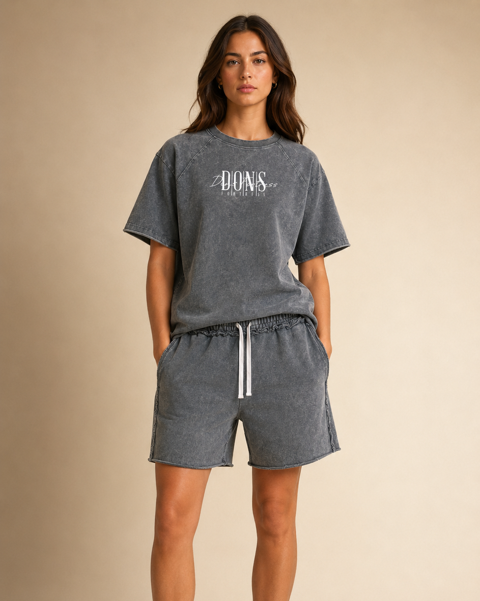 Woman wearing a gray oversized t-shirt and shorts set with branding on a beige background