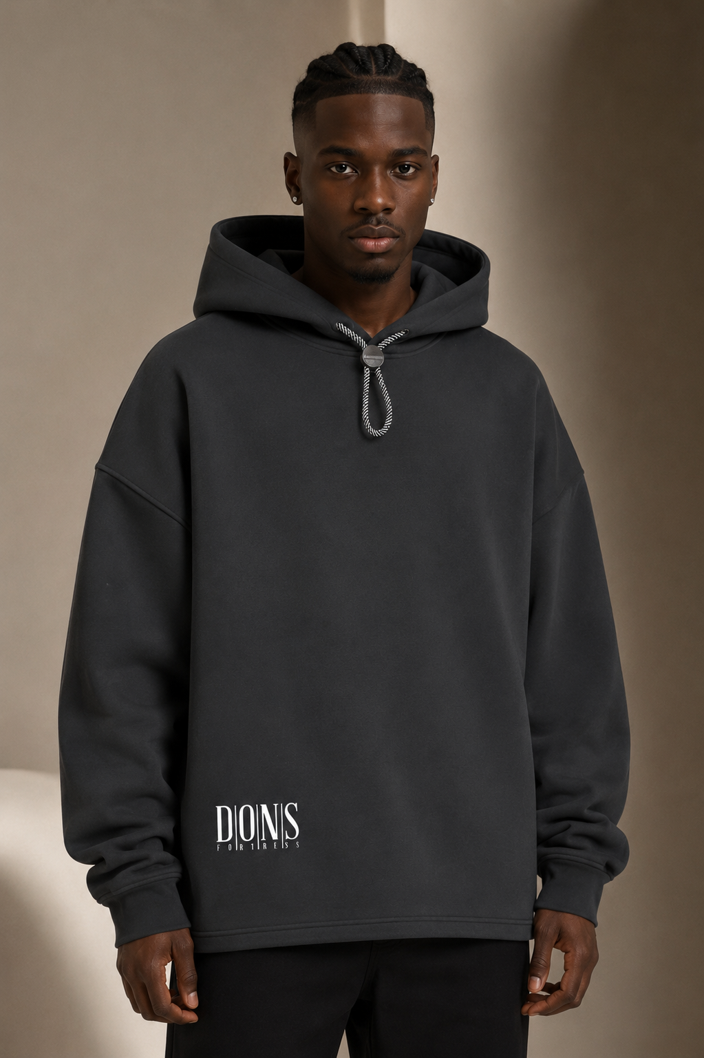 Man wearing a black hoodie with branding against a beige background