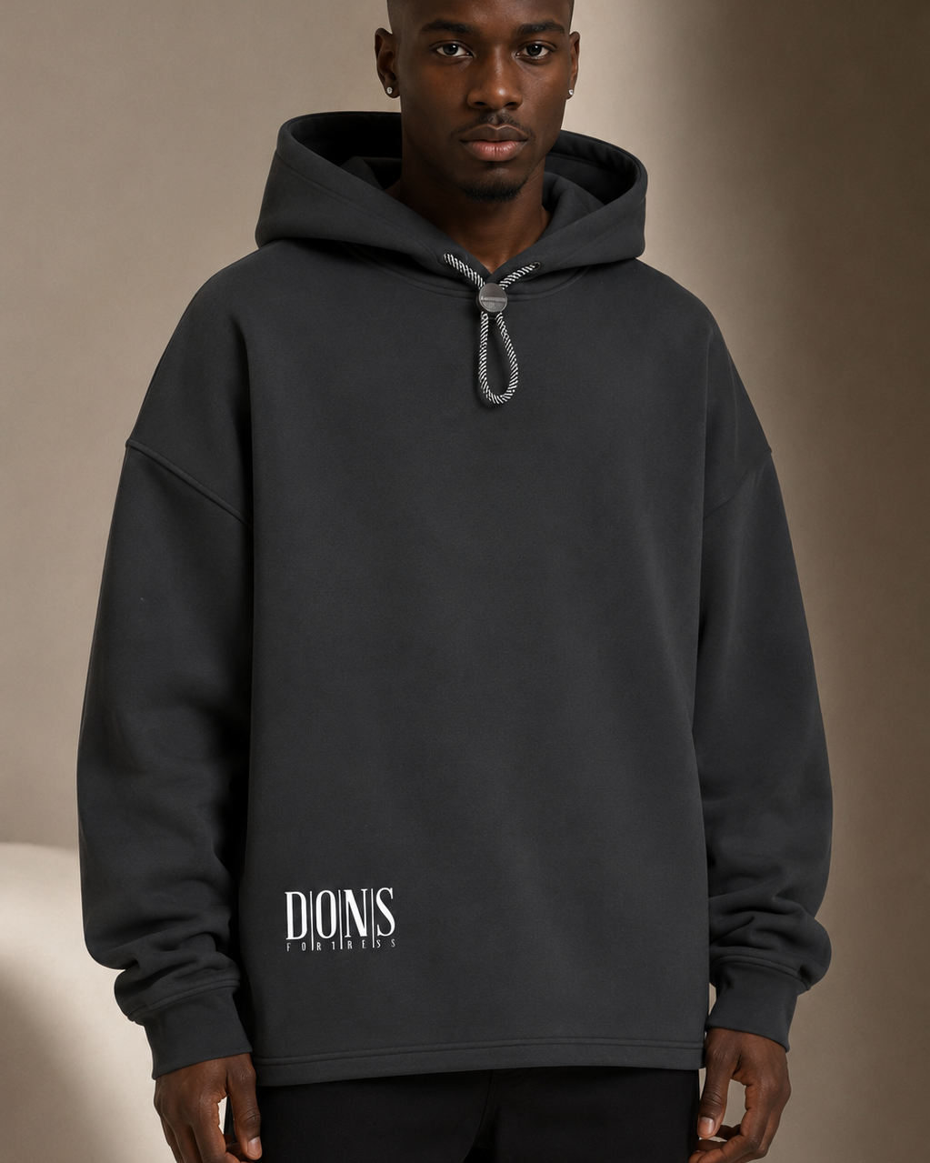 Man wearing a black hoodie with branding against a beige background