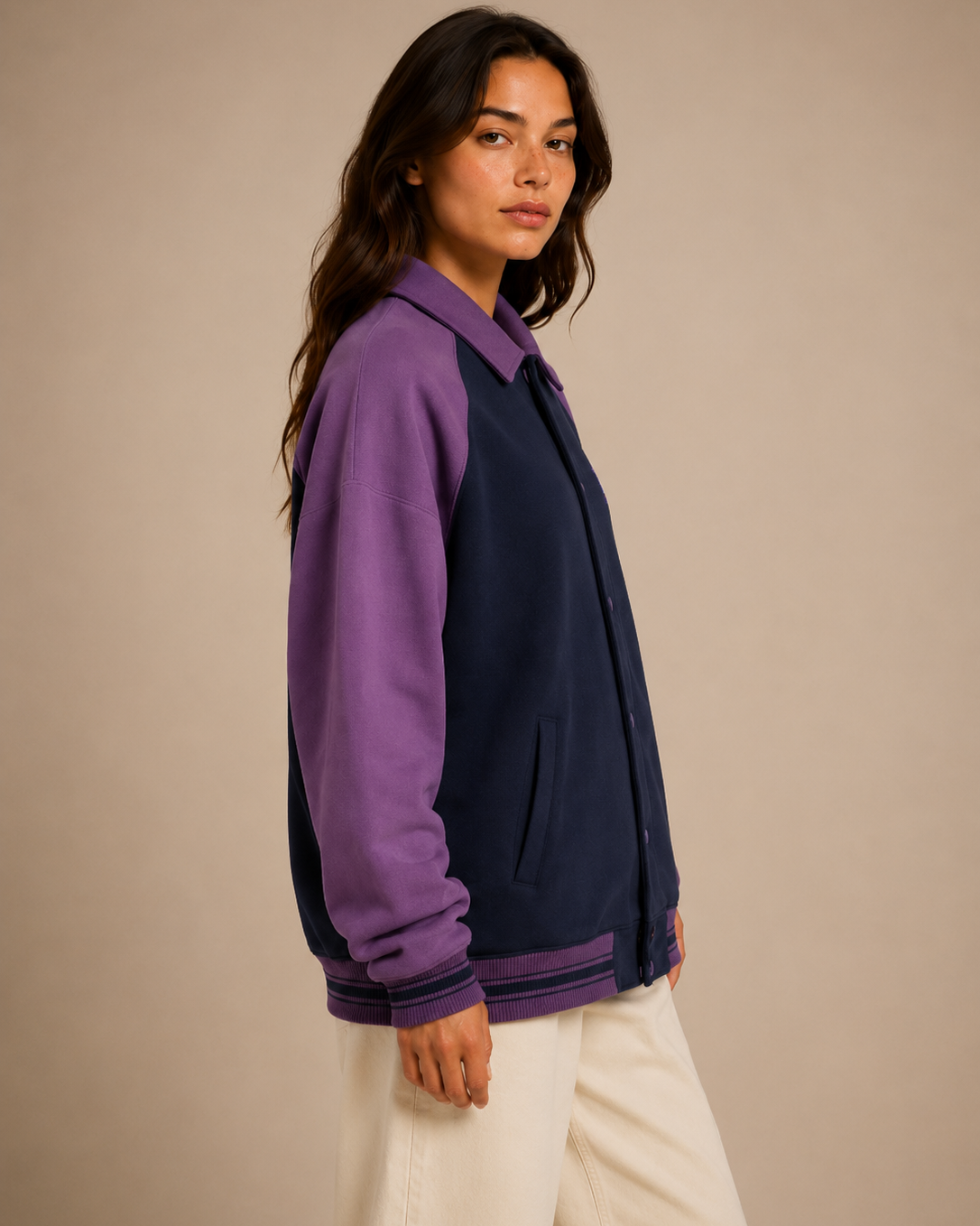 Woman wearing a two-tone jacket with purple sleeves and navy body against a beige background