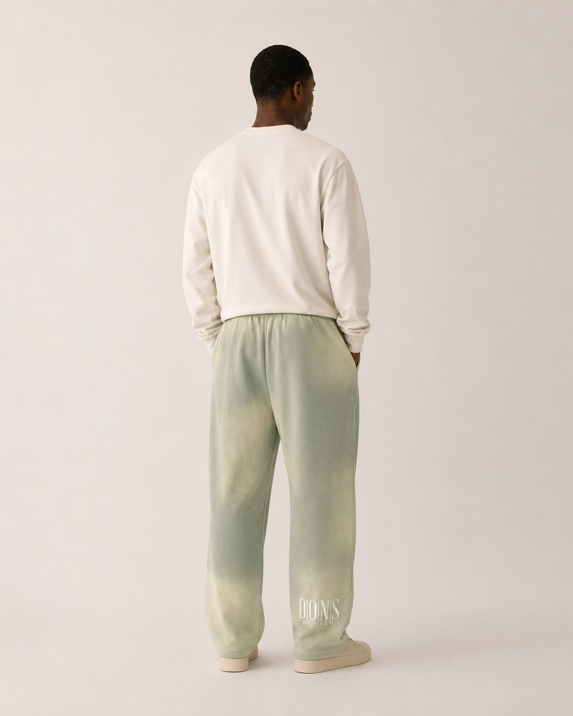 Person wearing a white sweatshirt and light green tie-dye pants on a plain background