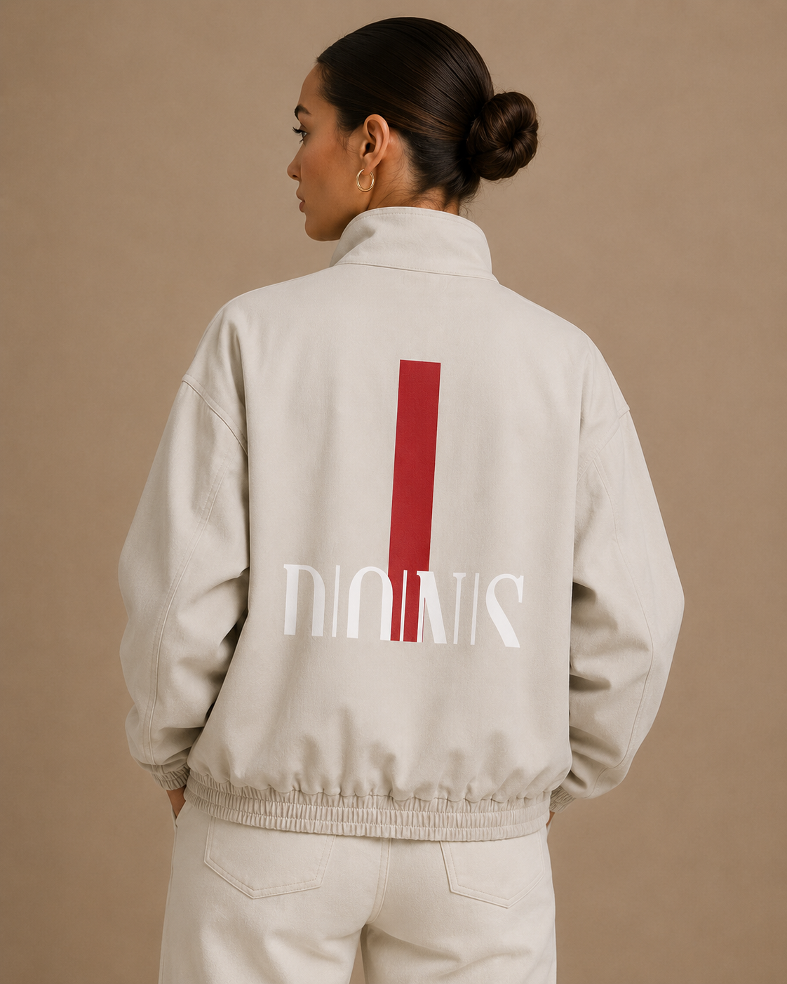 Person wearing a beige jacket with a red and white logo on the back against a beige background