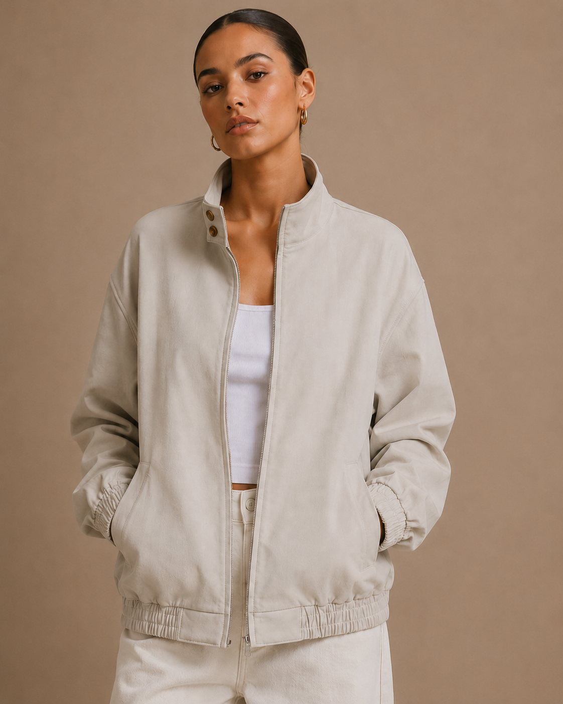 Woman wearing a beige jacket over a white top and pants on a brown background