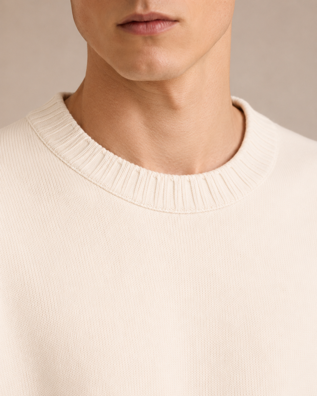 Close-up of a person wearing a beige sweater against a neutral background