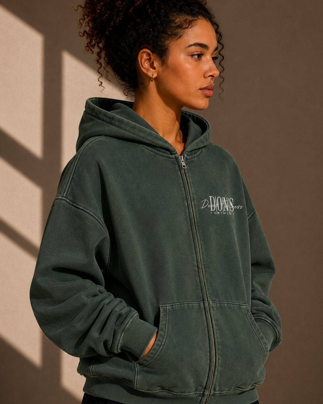 Person wearing a green hoodie with a logo against a neutral background