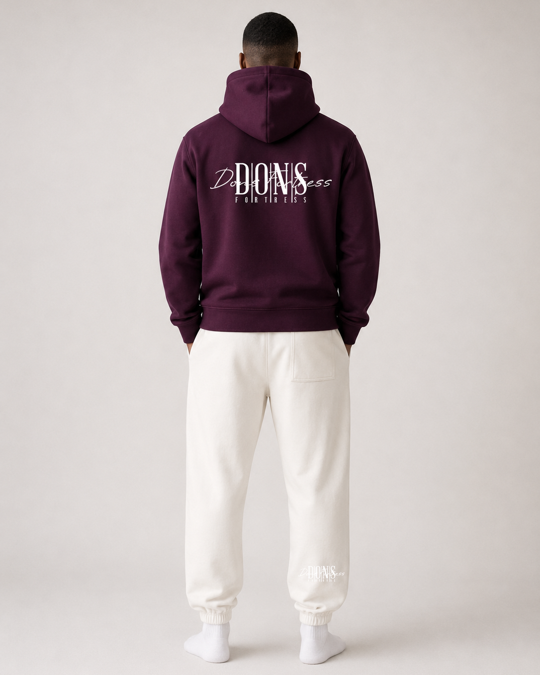 Person wearing a maroon hoodie with branding on the back, standing against a plain background