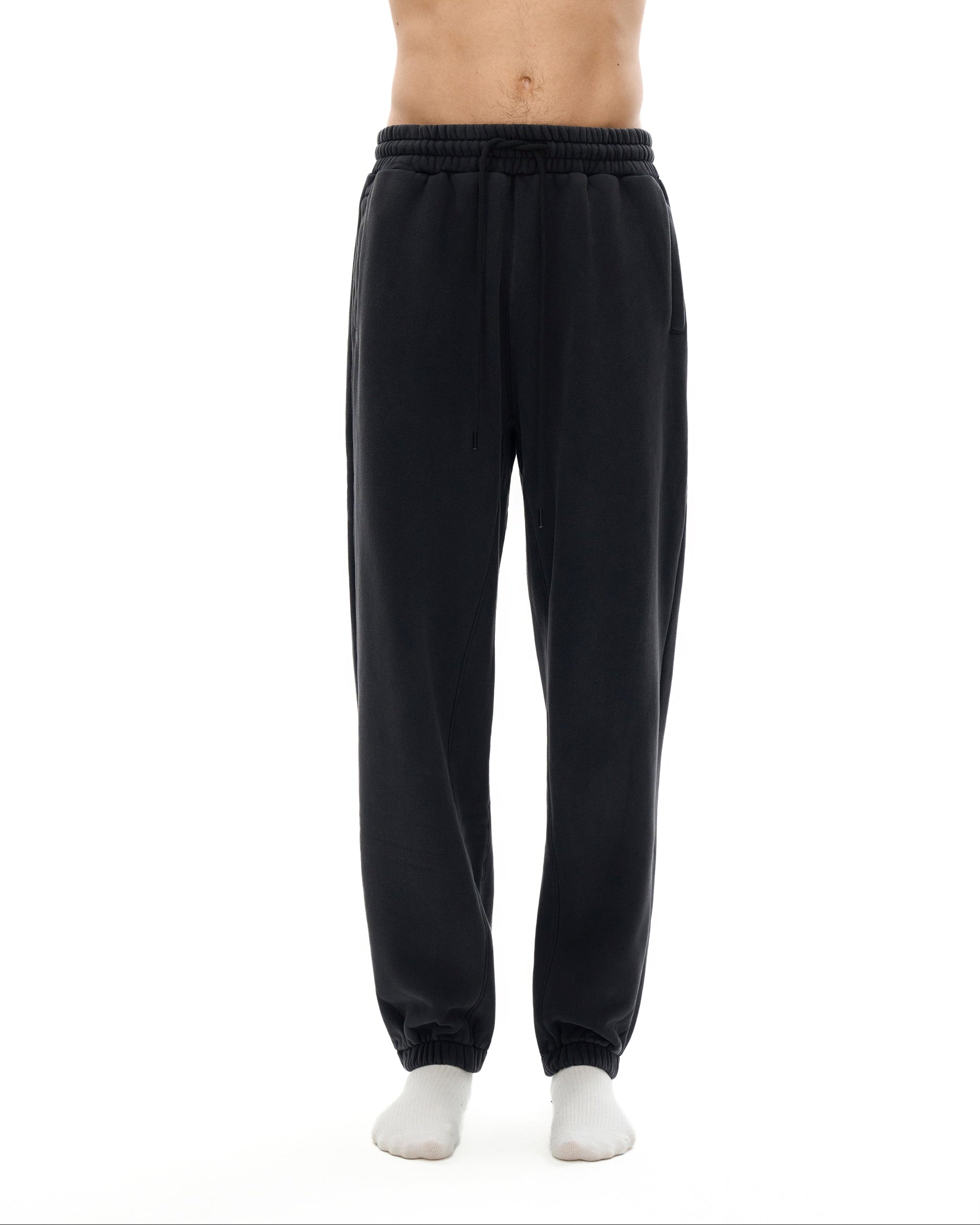 Black sweatpants worn by a person on a white background
