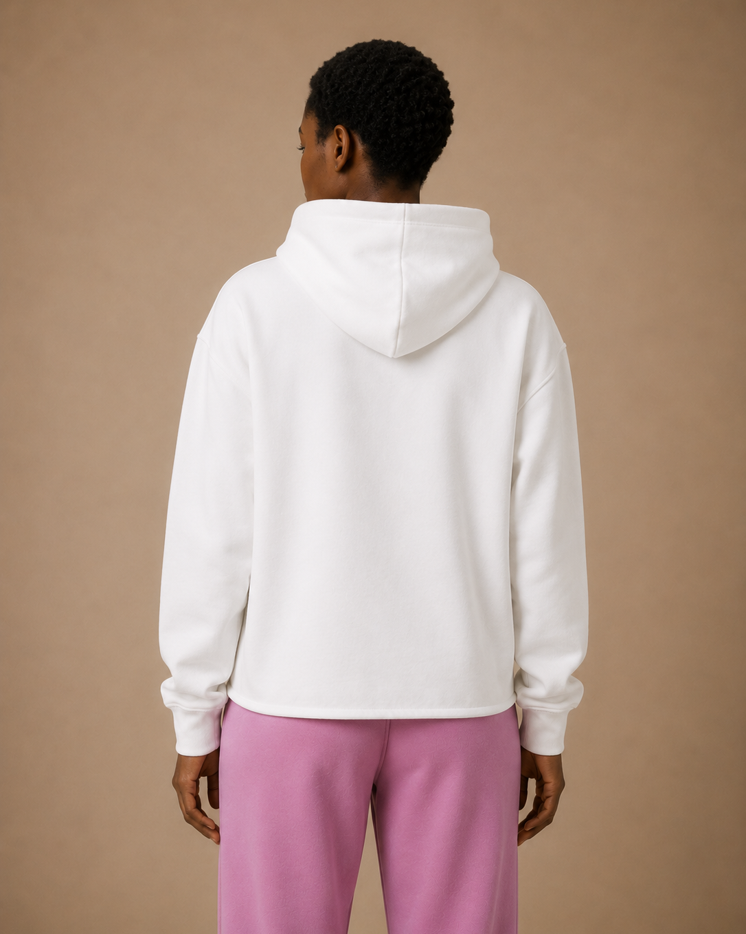 Person wearing a white hoodie and pink pants against a beige background