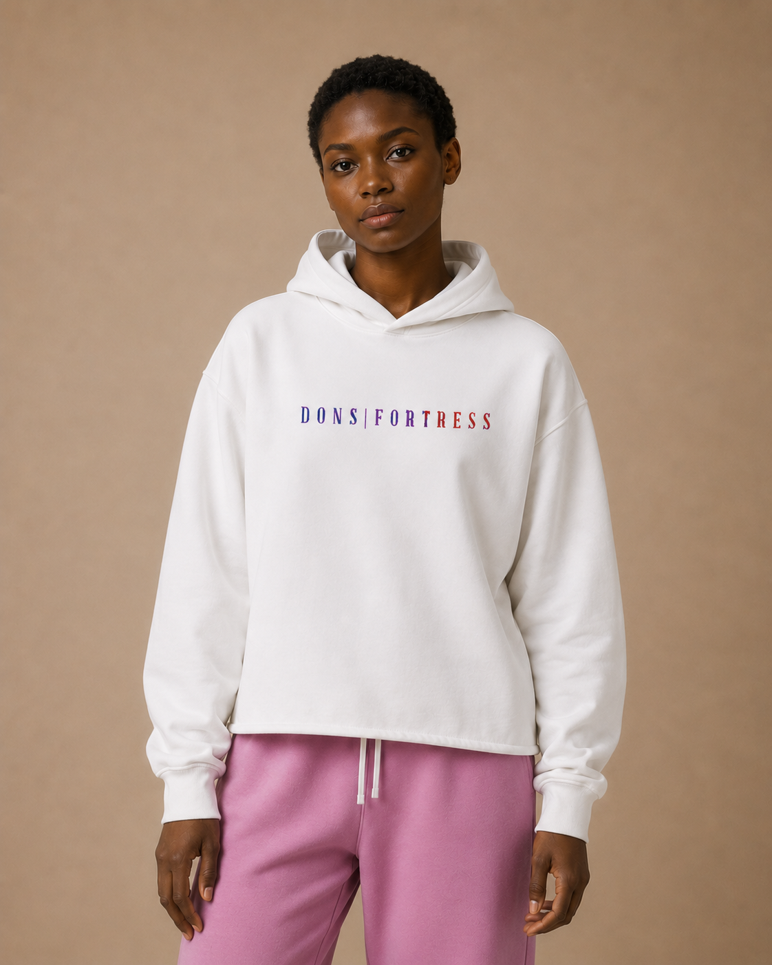 Person wearing a white hoodie with text and pink pants on a beige background