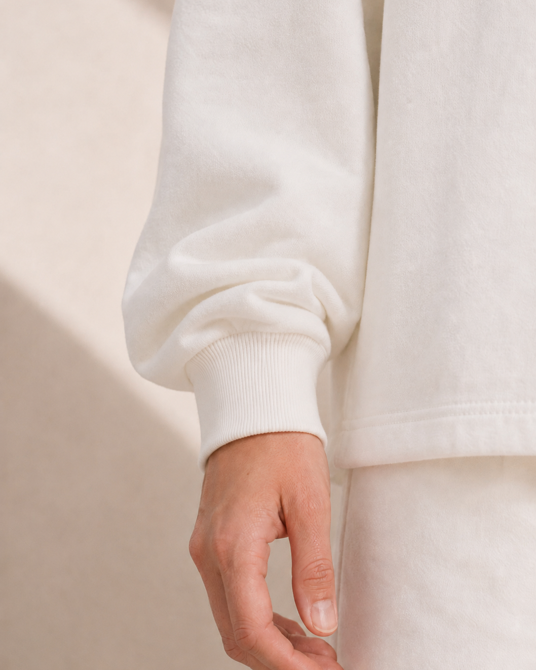 Close-up of a person wearing a white sweater with a neutral background