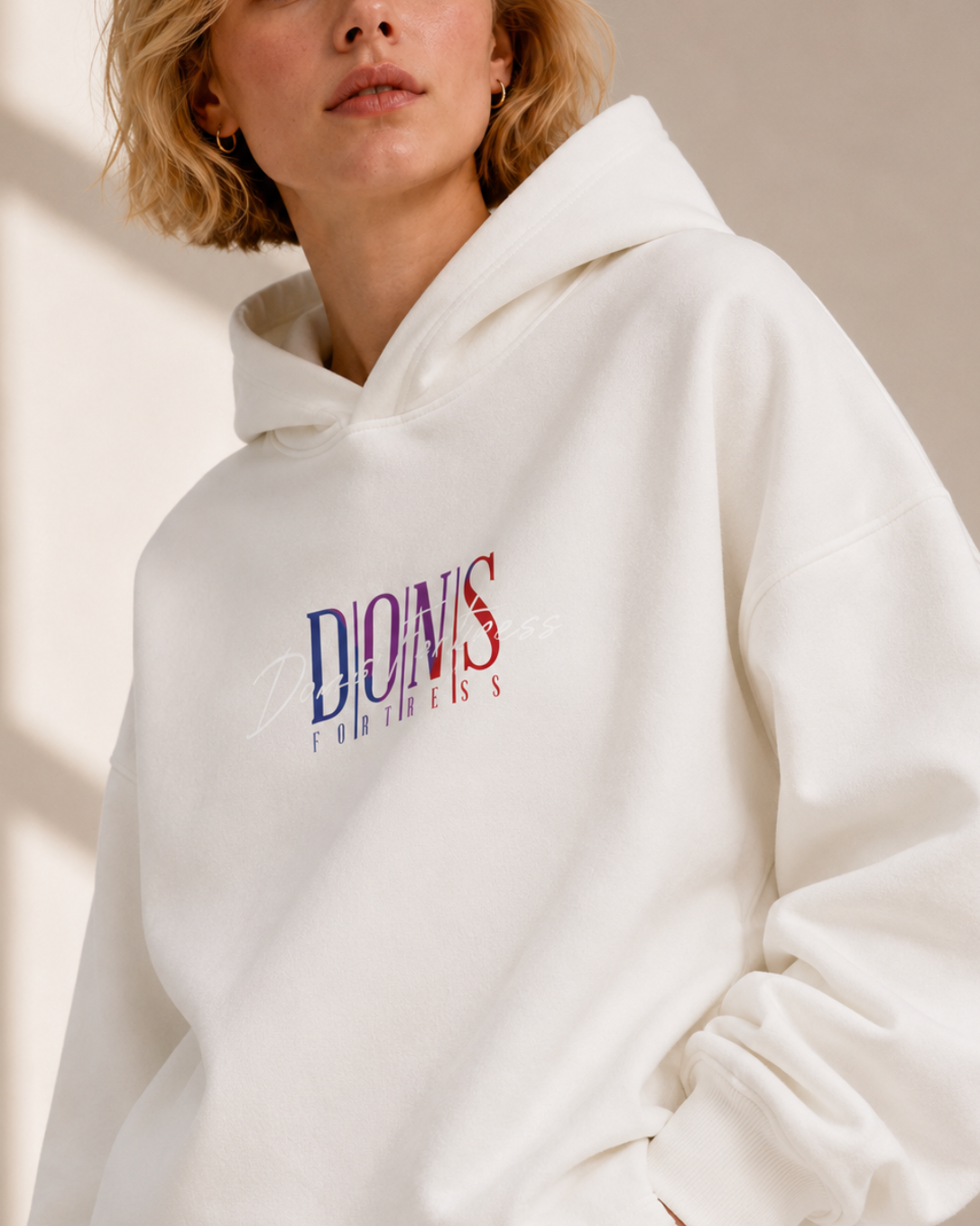 Person wearing a white hoodie with colourful text design on a neutral background