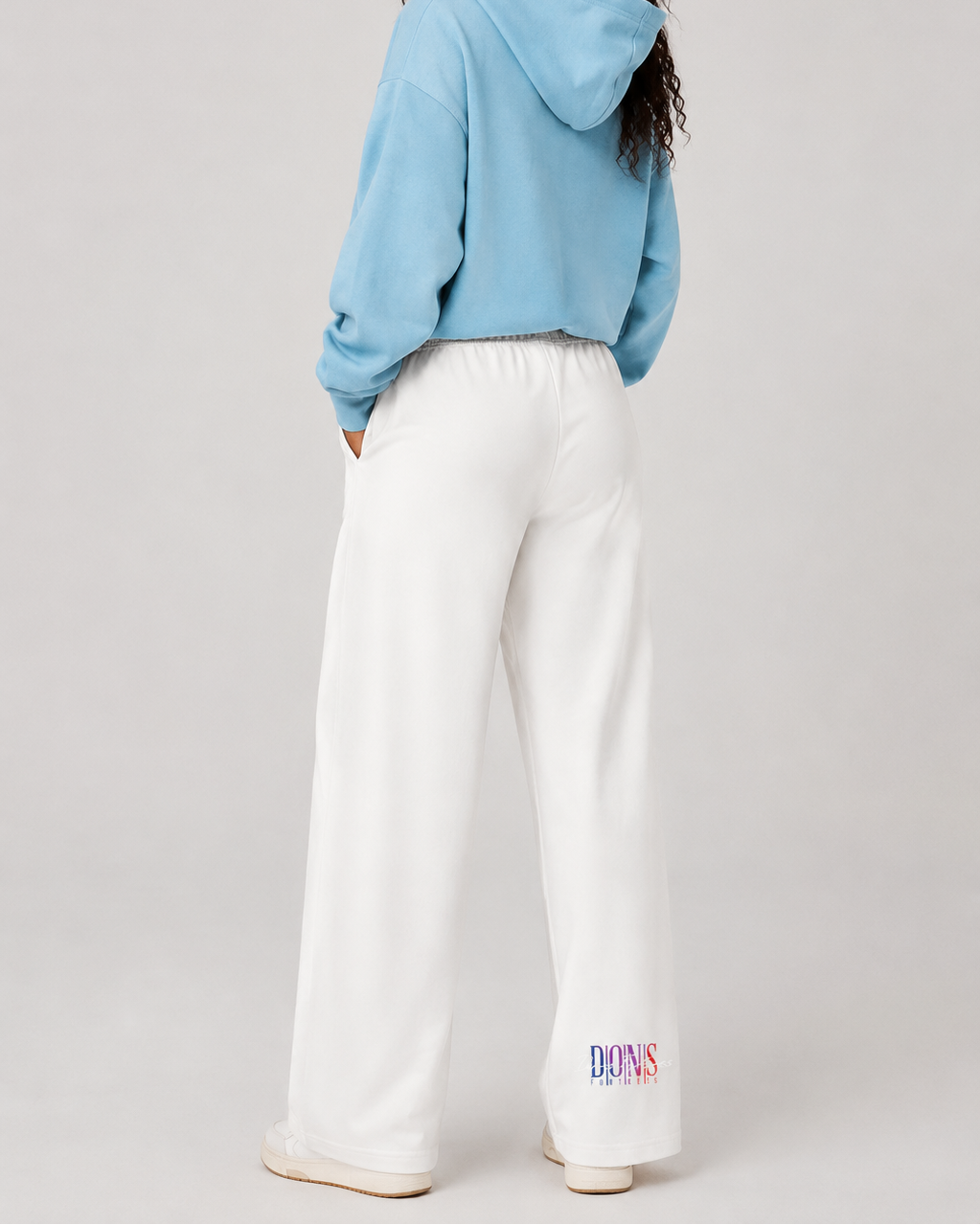 Person wearing a light blue hoodie and white pants on a plain background