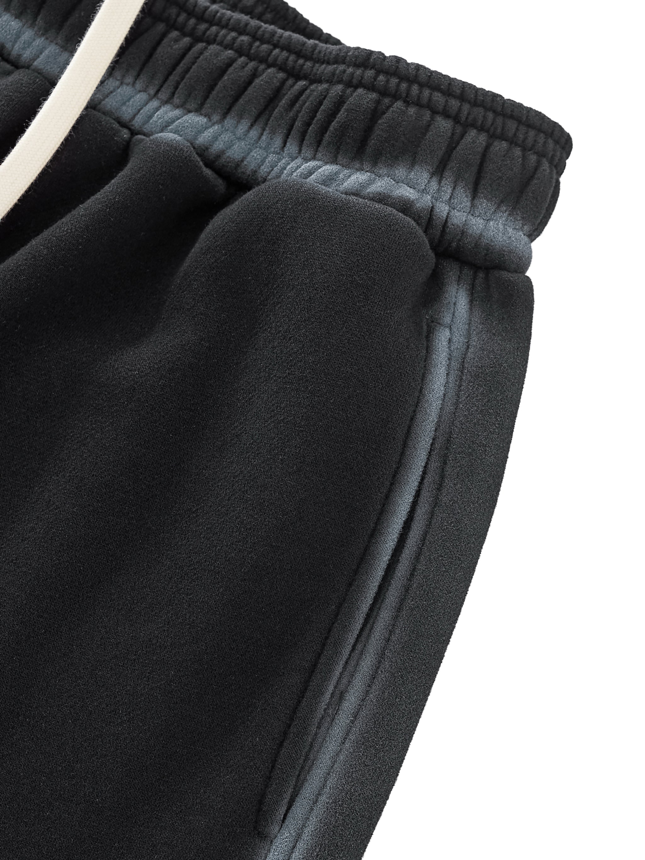 Close-up of dark gray sweatpants with a white drawstring on a white background