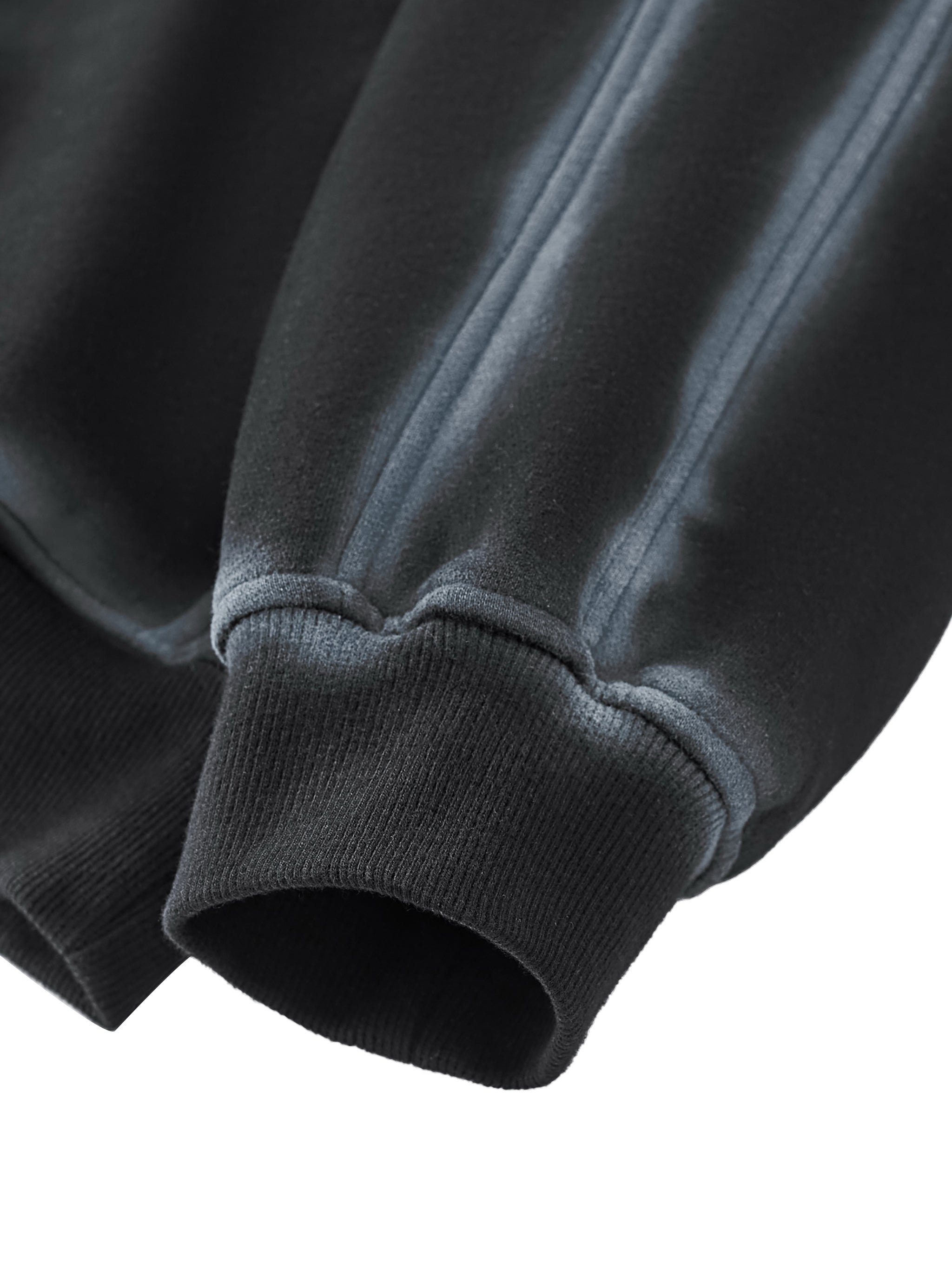 Close-up of a washed black sweatshirt with ribbed cuffs on a white background