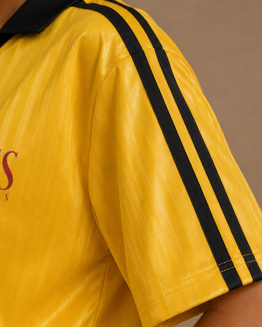 Yellow sports jersey with black stripes and branding on a brown background