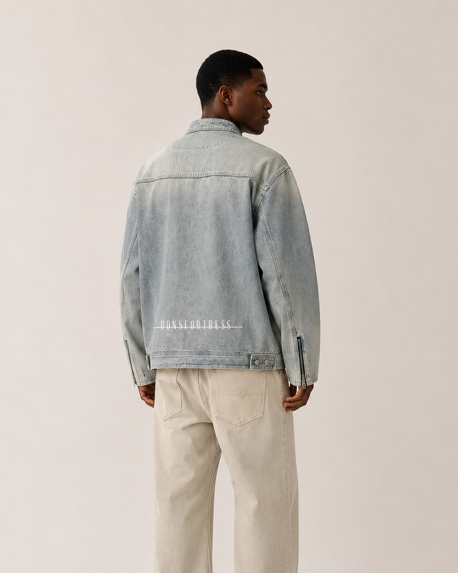 Person wearing a light blue denim jacket and beige pants on a plain background