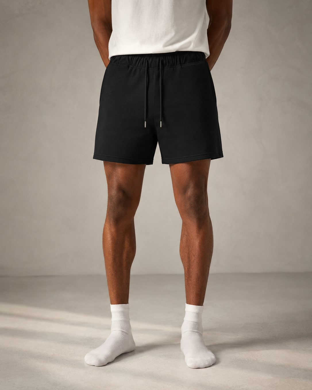 Person wearing black shorts and white socks on a neutral background