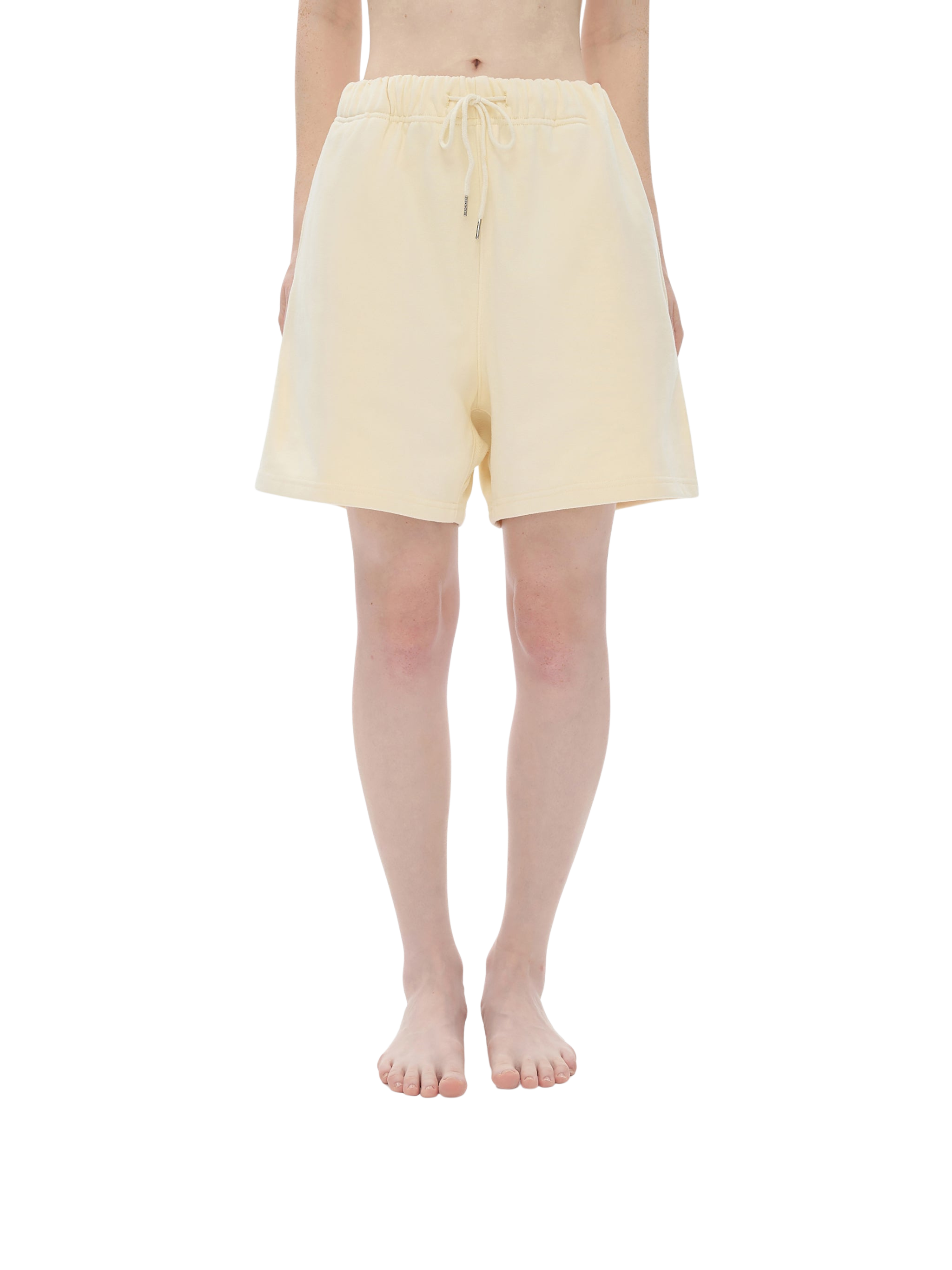 Person wearing light yellow shorts on a white background