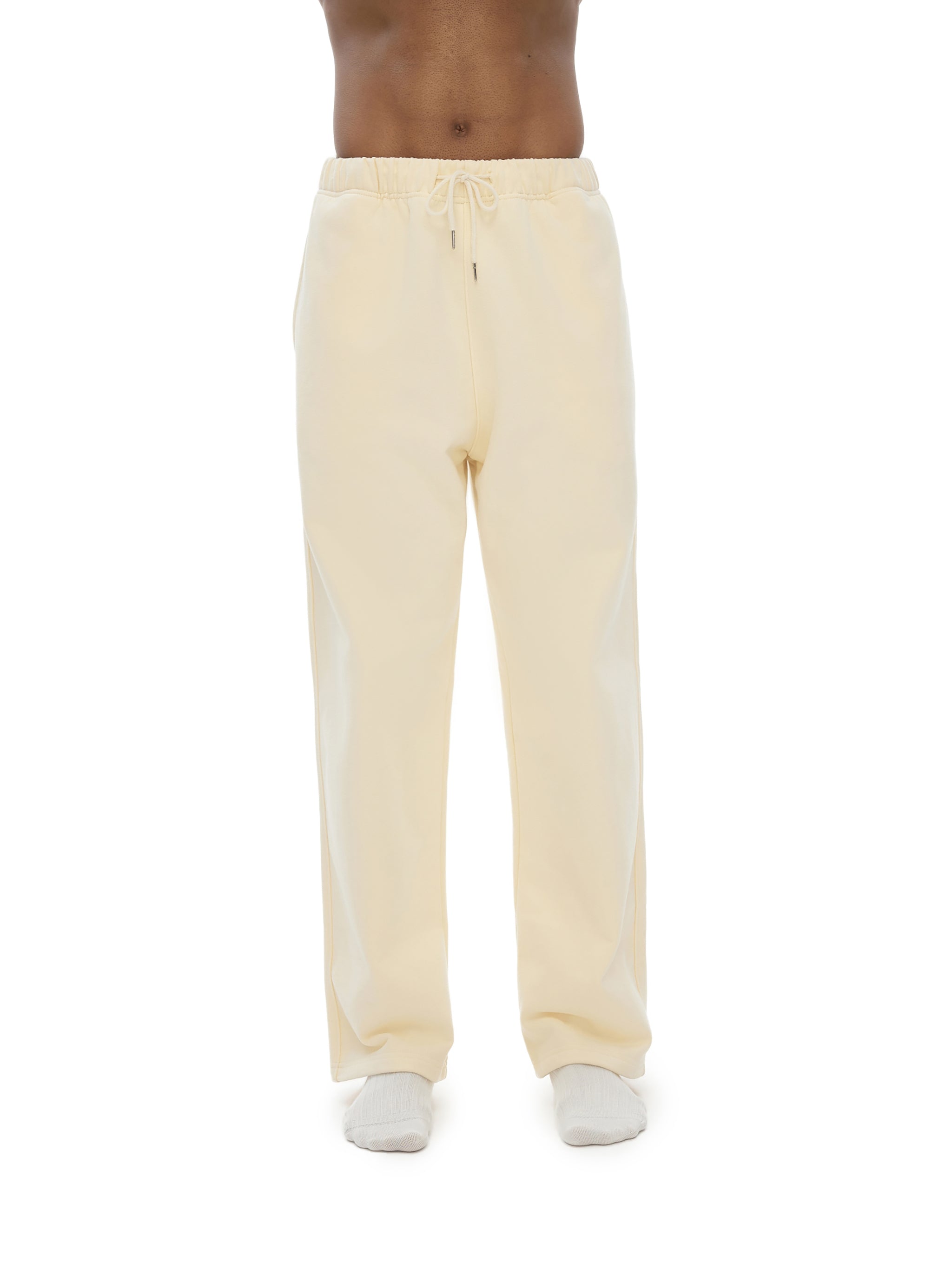 Light yellow sweatpants worn by a person on a white background