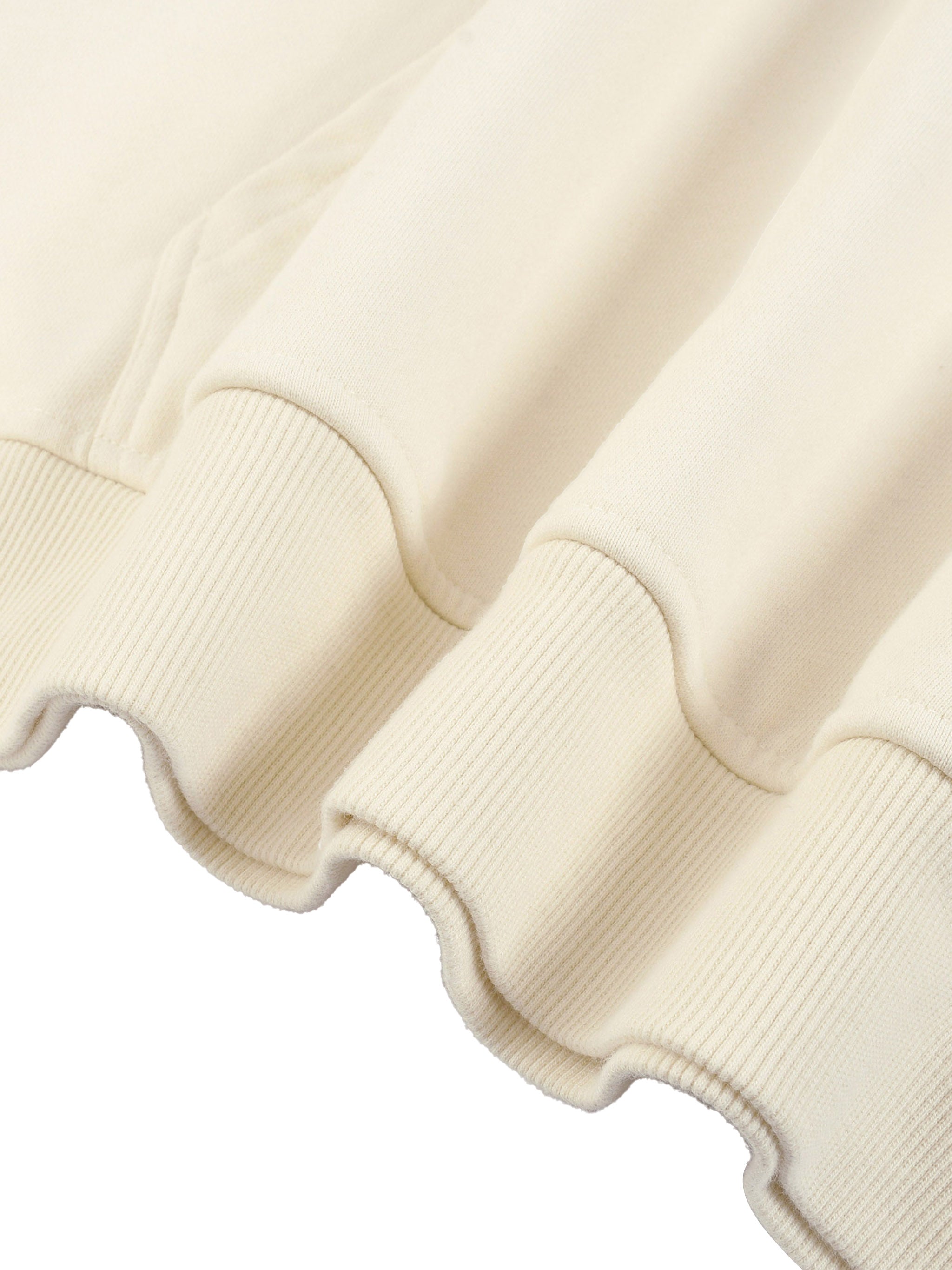 Close-up of a cream-coloured sweater with ribbed cuffs and hem on a white background