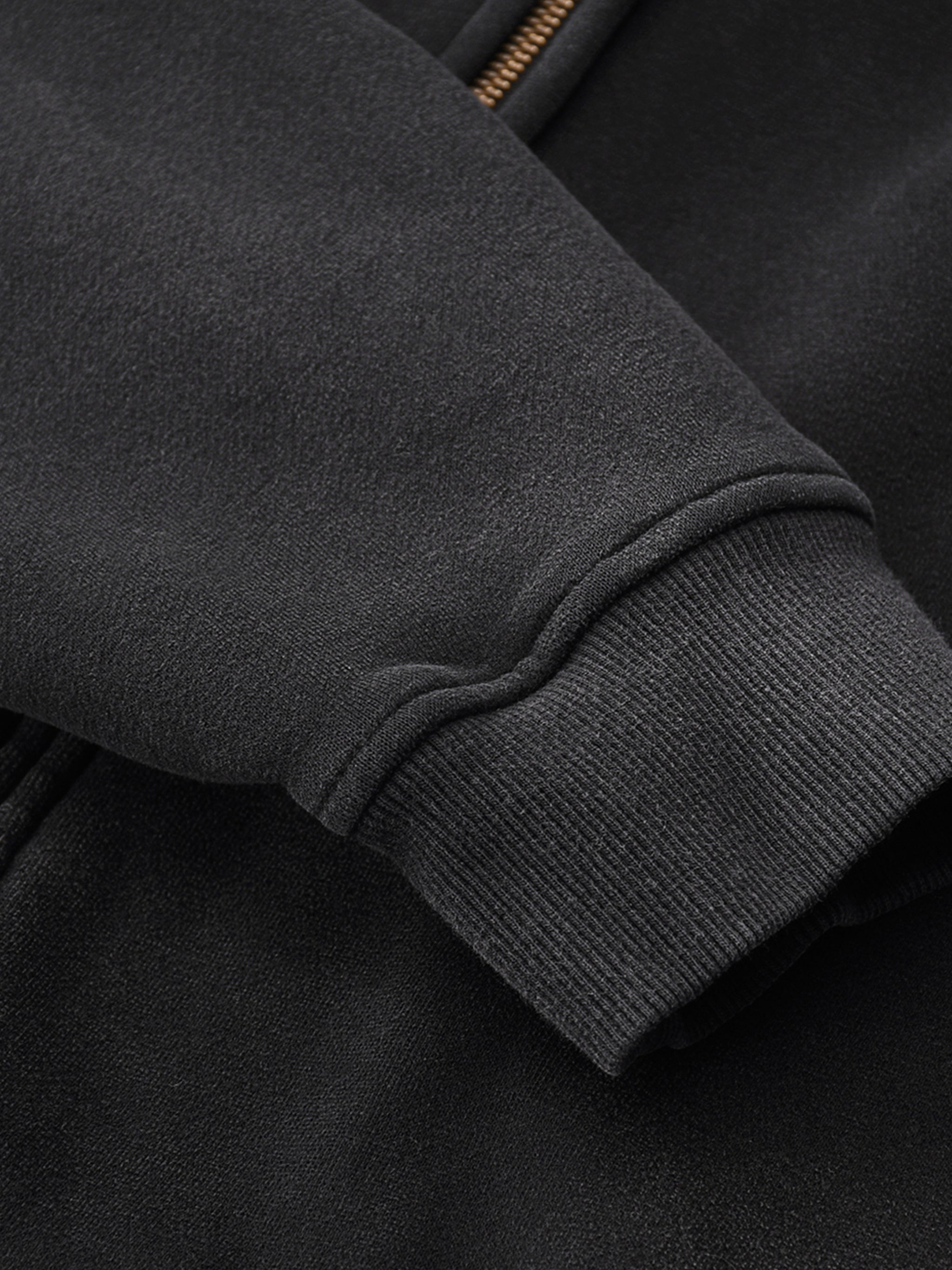 Close-up of a dark gray jacket sleeve with a zip detail.