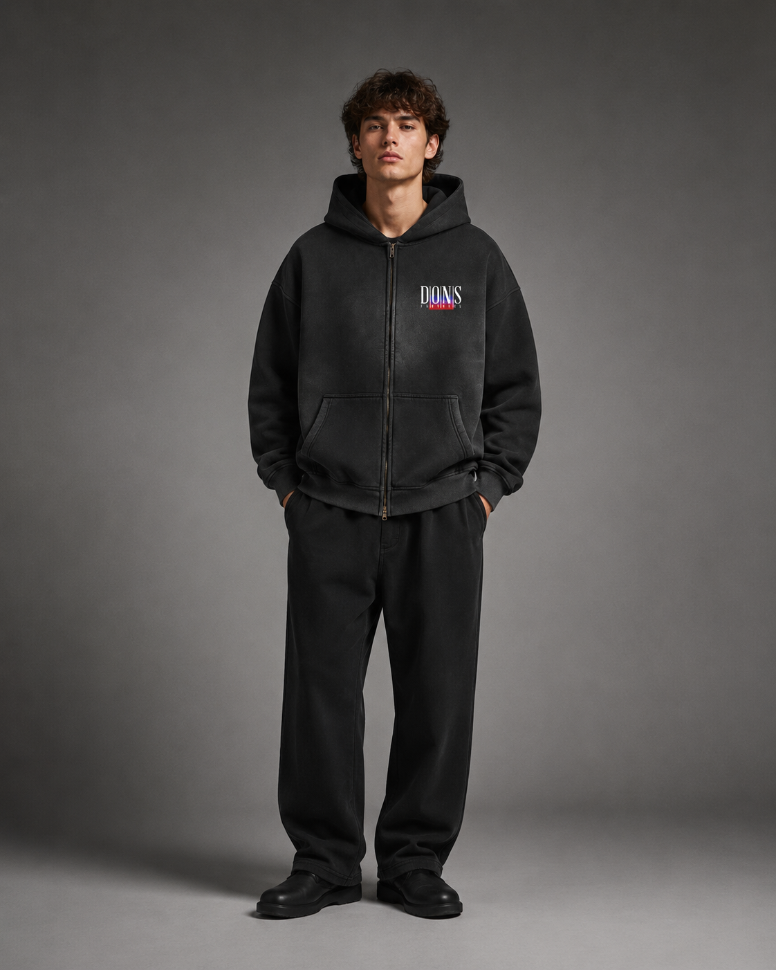 Person wearing a black hoodie with a logo on a gray background